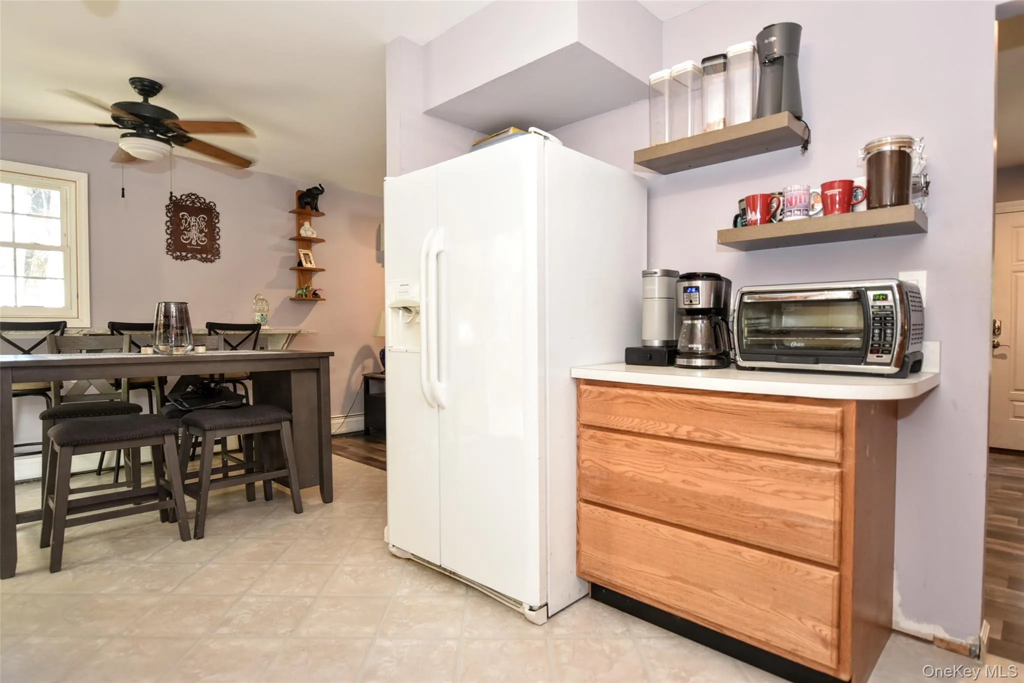 Kitchen featuring white refrigerator with ice dispenser, light countertops, open shelves, and a ceiling fan Kitchen featuring white refrigerator with ice dispenser, light countertops, open shelves, and a ceiling fan
