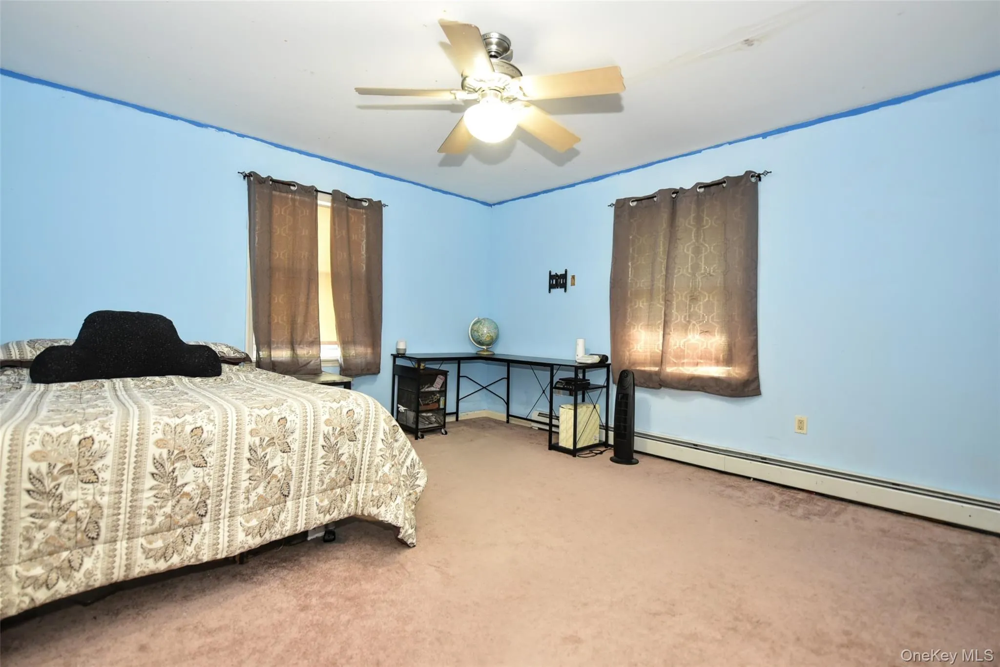 Carpeted bedroom featuring a ceiling fan and a baseboard heating unit Carpeted bedroom featuring a ceiling fan and a baseboard heating unit
