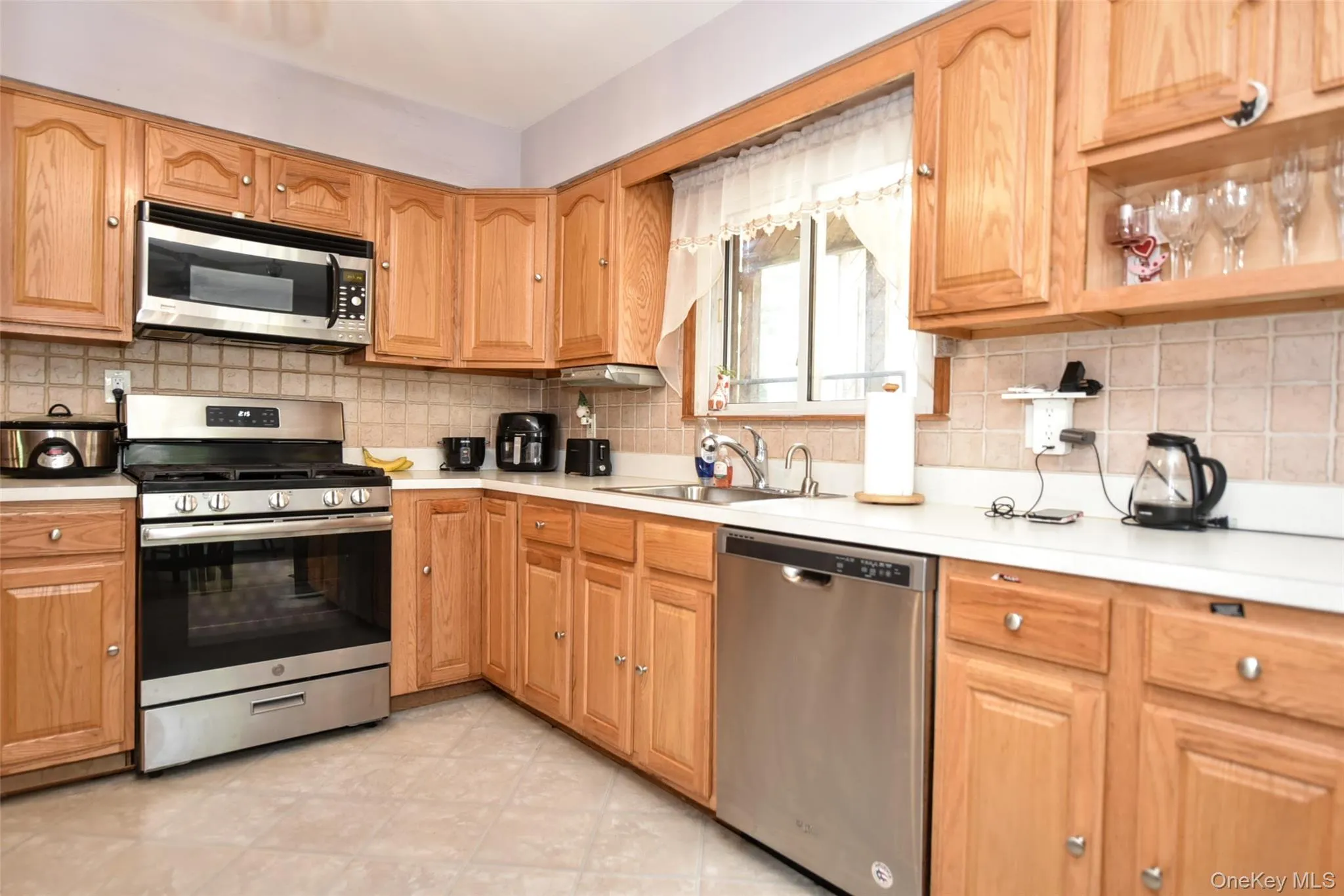 Kitchen featuring appliances with stainless steel finishes, backsplash, and light countertops Kitchen featuring appliances with stainless steel finishes, backsplash, and light countertops
