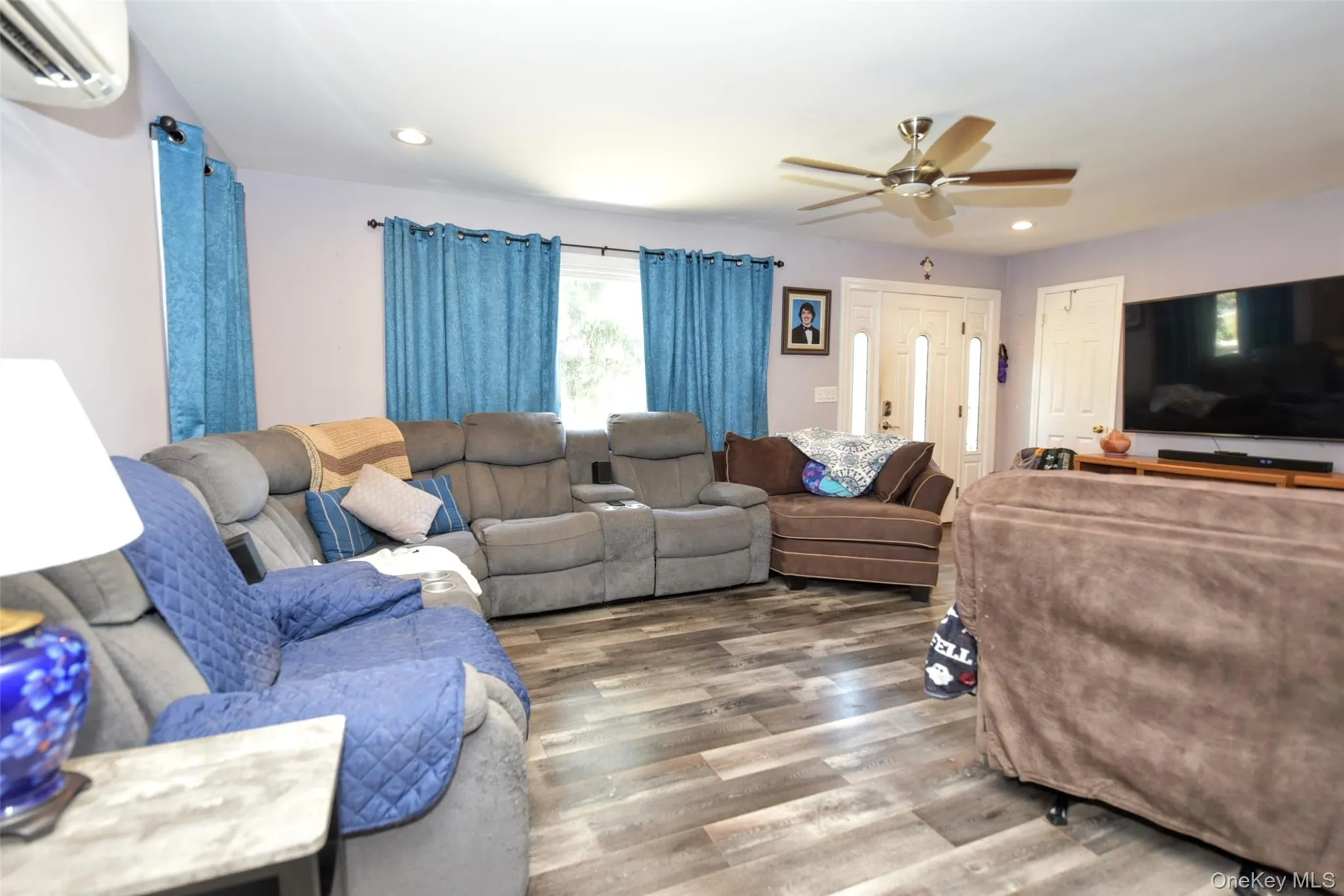 Living room with a wall mounted AC, recessed lighting, wood finished floors, and a ceiling fan Living room with a wall mounted AC, recessed lighting, wood finished floors, and a ceiling fan