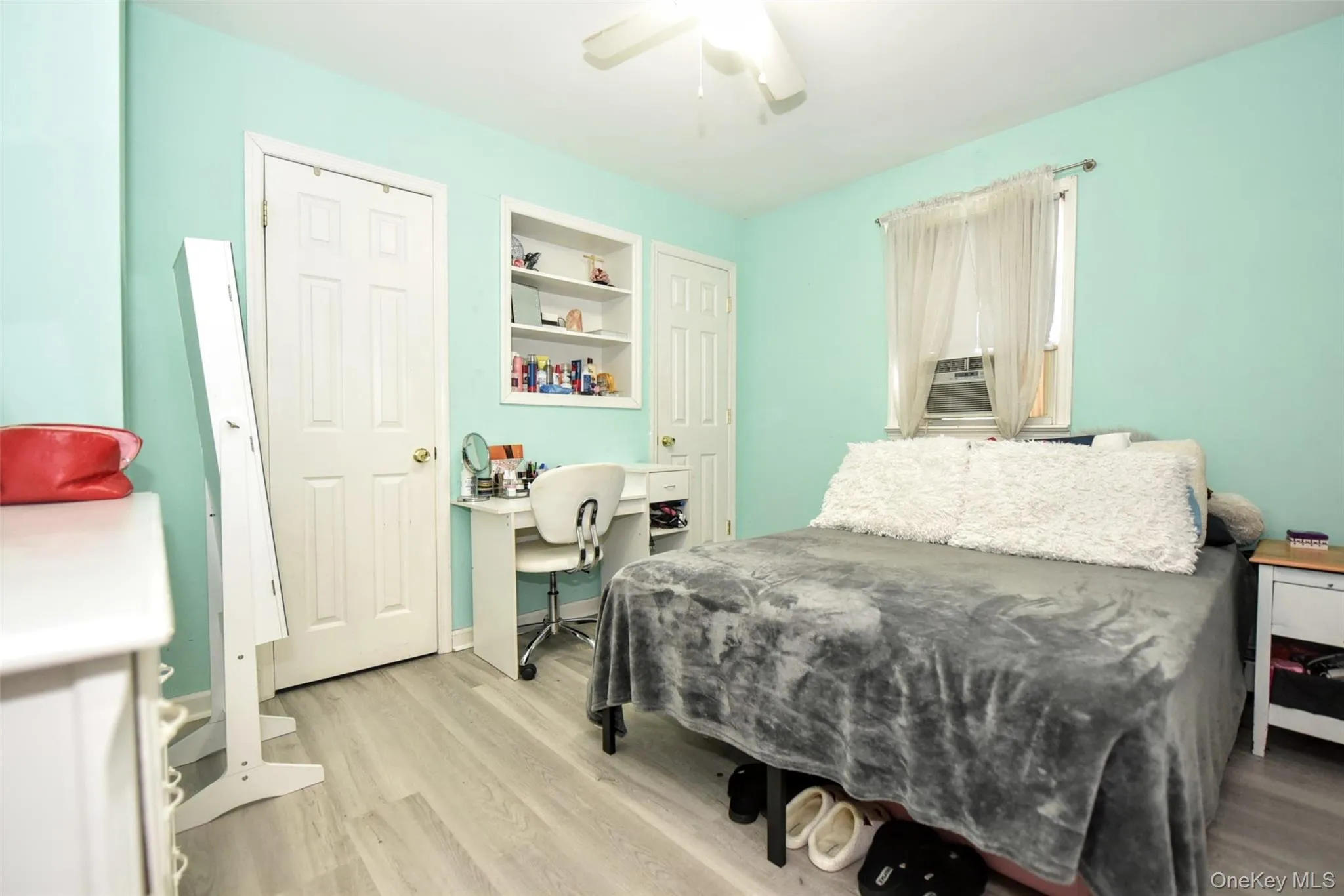 Bedroom with light wood-type flooring, an office area, a ceiling fan, and cooling unit Bedroom with light wood-type flooring, an office area, a ceiling fan, and cooling unit