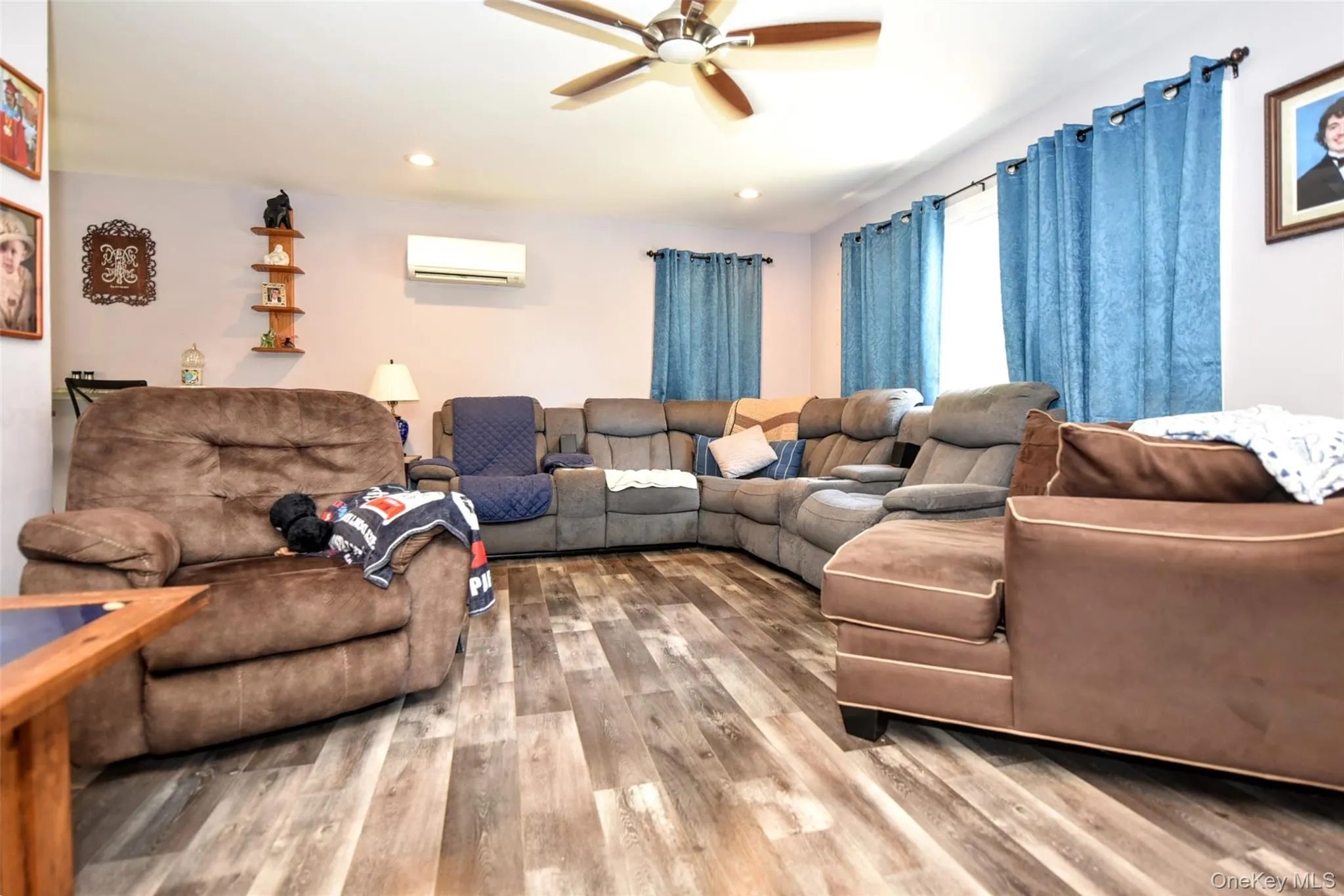 Living area featuring wood finished floors, recessed lighting, a ceiling fan, and a wall unit AC Living area featuring wood finished floors, recessed lighting, a ceiling fan, and a wall unit AC