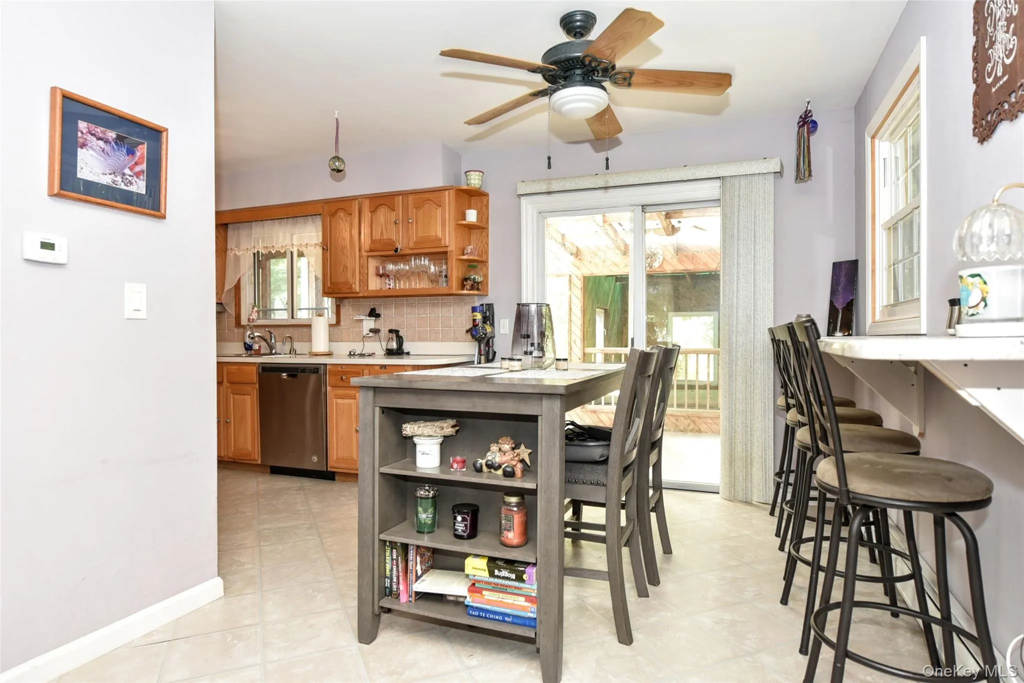 Kitchen featuring open shelves, light countertops, a breakfast bar, and brown cabinetry Kitchen featuring open shelves, light countertops, a breakfast bar, and brown cabinetry