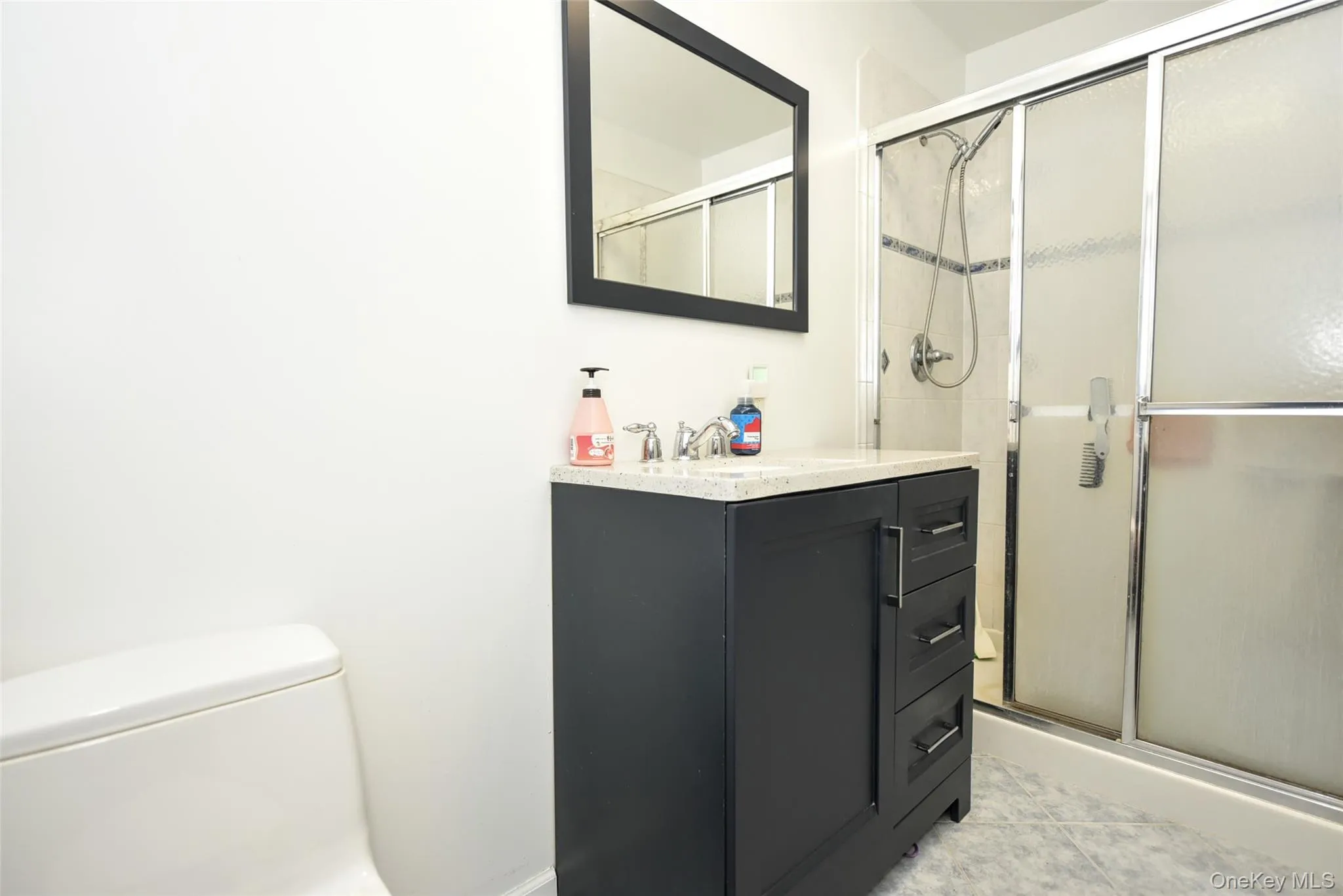 Bathroom featuring vanity, a stall shower, and light tile patterned floors Bathroom featuring vanity, a stall shower, and light tile patterned floors