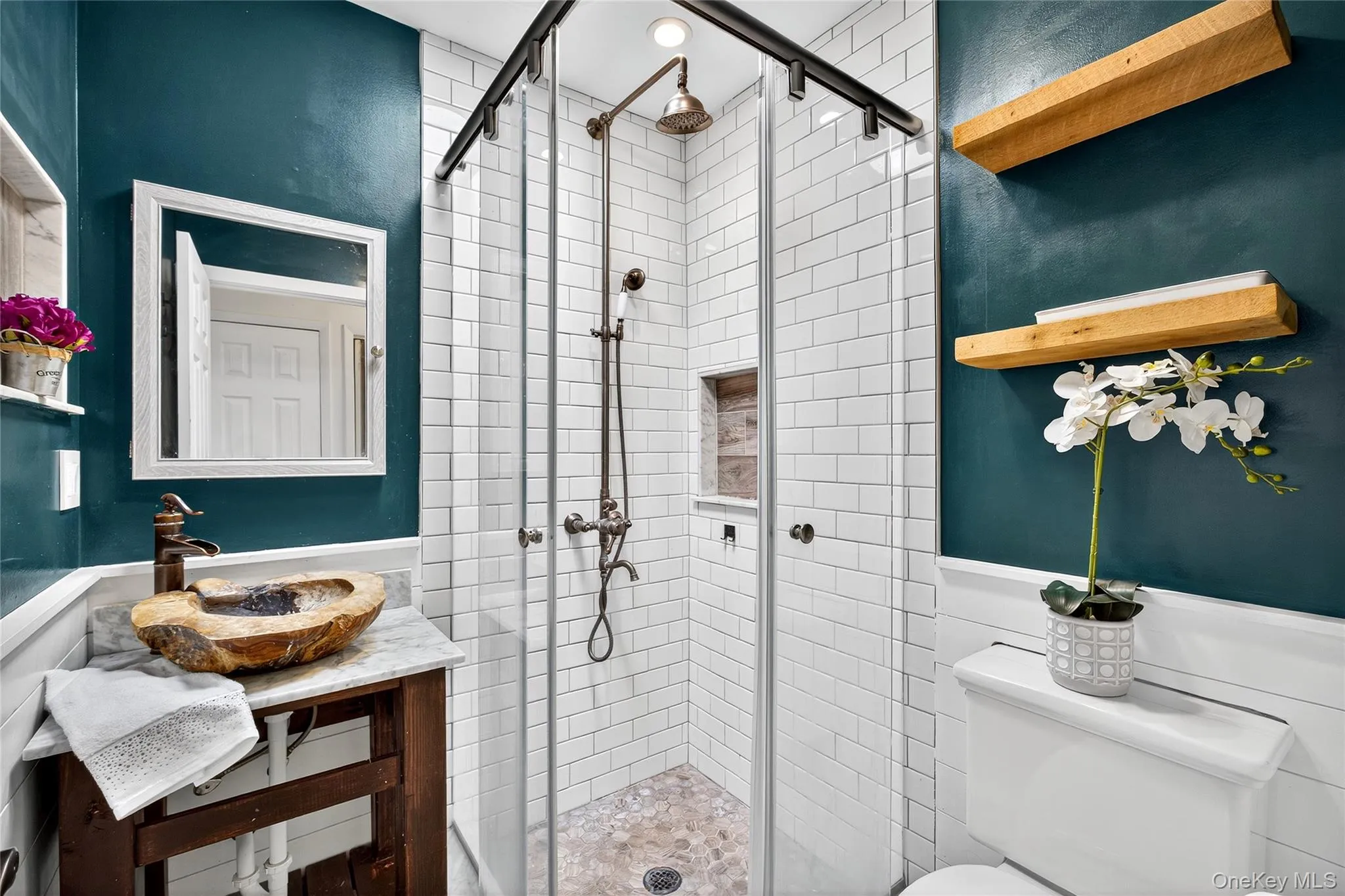 Full bathroom featuring a shower stall, vanity, and a wainscoted wall Full bathroom featuring a shower stall, vanity, and a wainscoted wall
