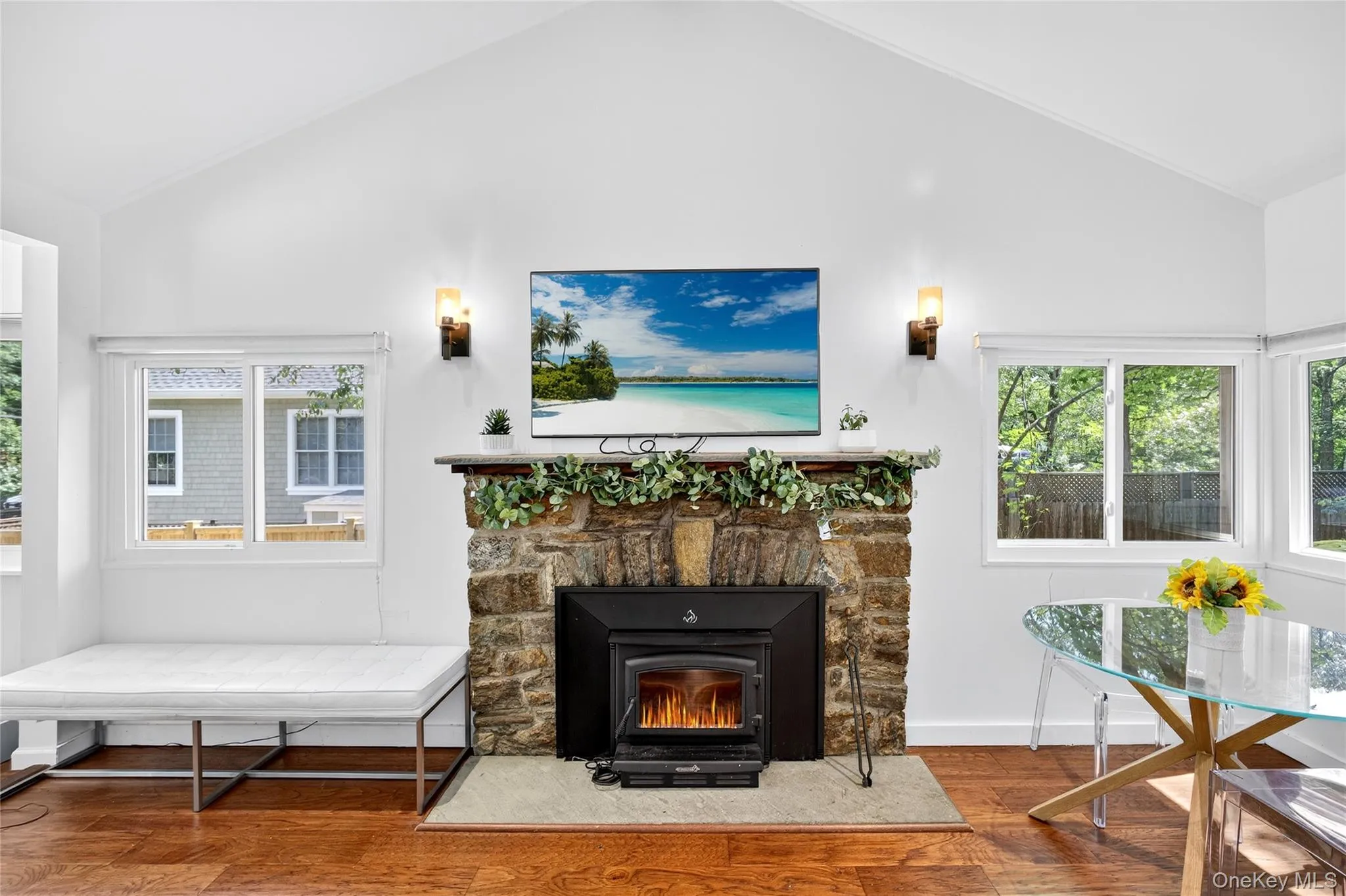 Living area featuring vaulted ceiling, wood finished floors, and plenty of natural light Living area featuring vaulted ceiling, wood finished floors, and plenty of natural light
