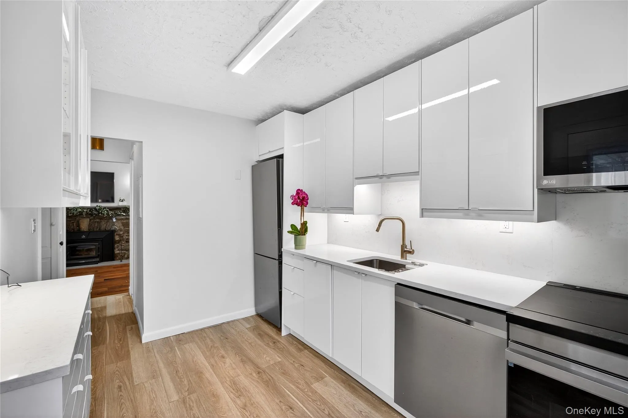 Brand New Kitchen with modern cabinets, Quartz Counters, stainless steel appliances, white cabinetry, light wood-style floors, and a textured ceiling Brand New Kitchen with modern cabinets, Quartz Counters, stainless steel appliances, white cabinetry, light wood-style floors, and a textured ceiling