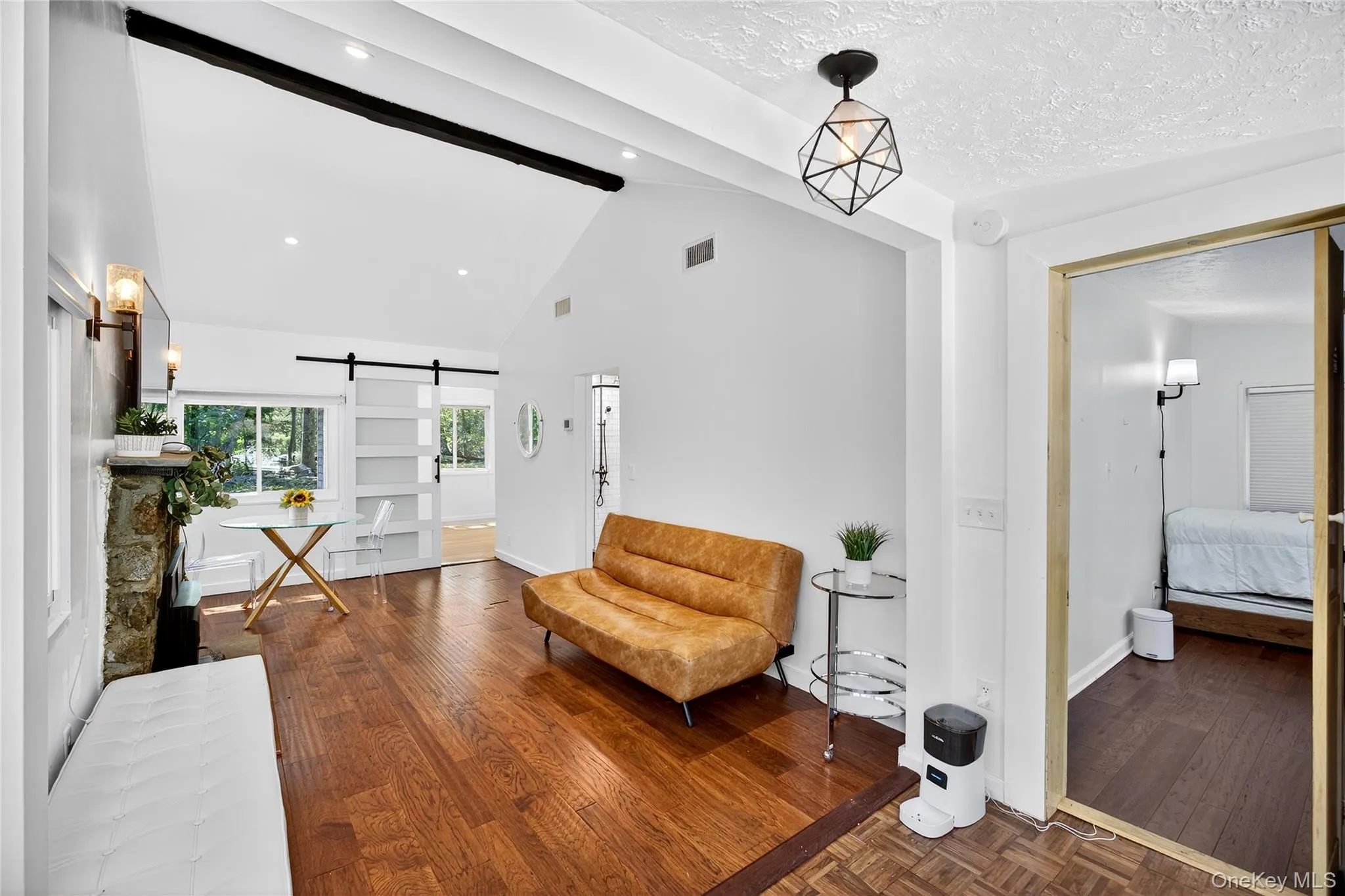 Living room with dark wood finished floors, a barn door, beamed ceiling, and high vaulted ceiling Living room with dark wood finished floors, a barn door, beamed ceiling, and high vaulted ceiling