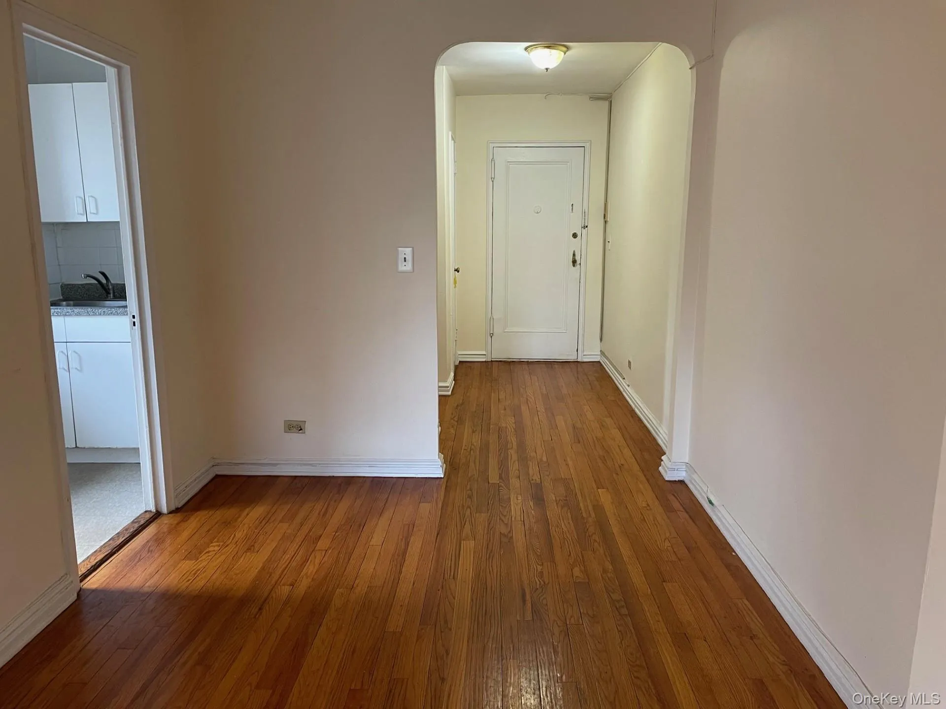 Hallway featuring hardwood / wood-style floors and arched walkways Hallway featuring hardwood / wood-style floors and arched walkways