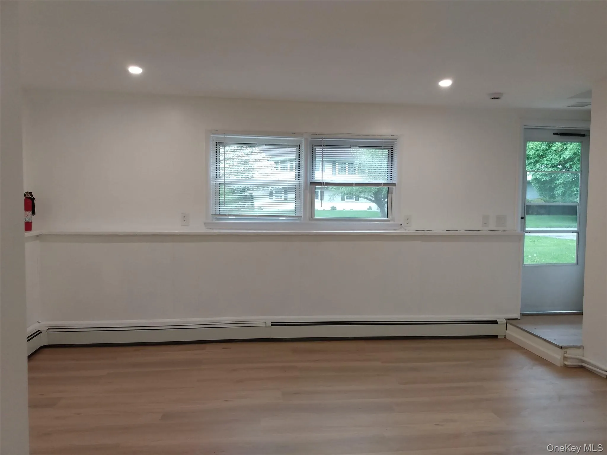 Unfurnished room featuring healthy amount of natural light, recessed lighting, light wood-style floors, and a baseboard radiator Unfurnished room featuring healthy amount of natural light, recessed lighting, light wood-style floors, and a baseboard radiator