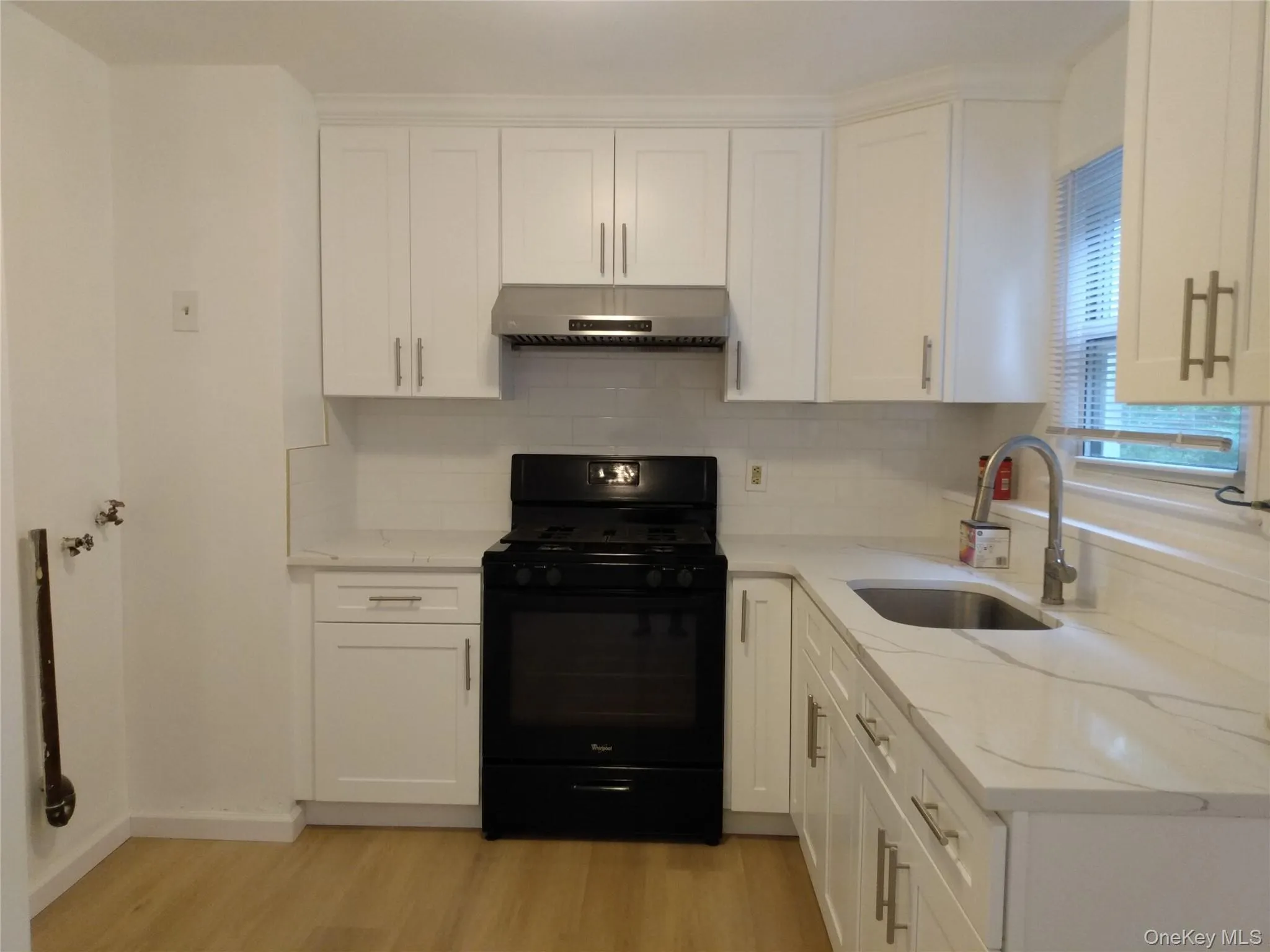 Kitchen with black gas range, white cabinets, light stone counters, and light color flooring Kitchen with black gas range, white cabinets, light stone counters, and light color flooring