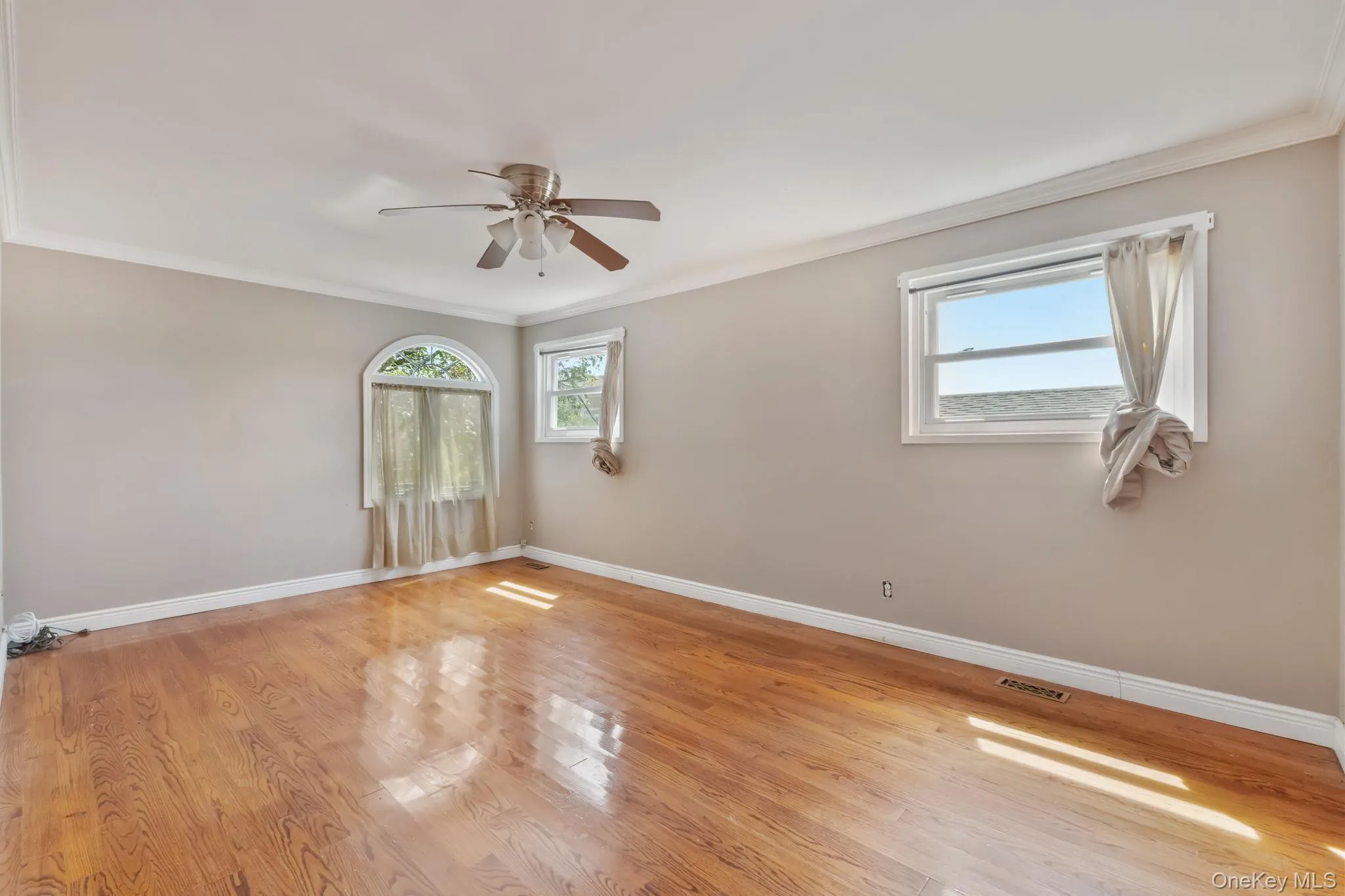 Empty room featuring ornamental molding, light wood finished floors, and ceiling fan Empty room featuring ornamental molding, light wood finished floors, and ceiling fan