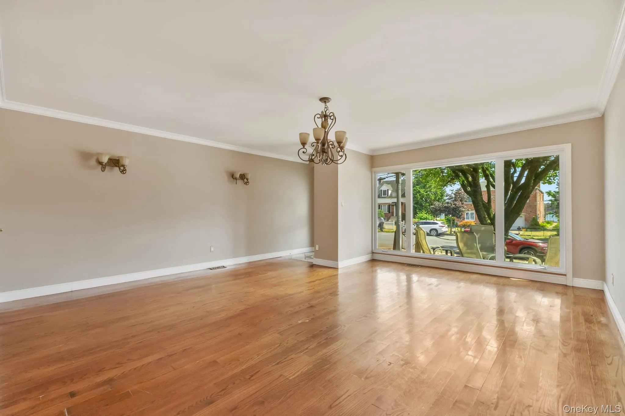 Empty room featuring ornamental molding, a chandelier, and light wood finished floors Empty room featuring ornamental molding, a chandelier, and light wood finished floors