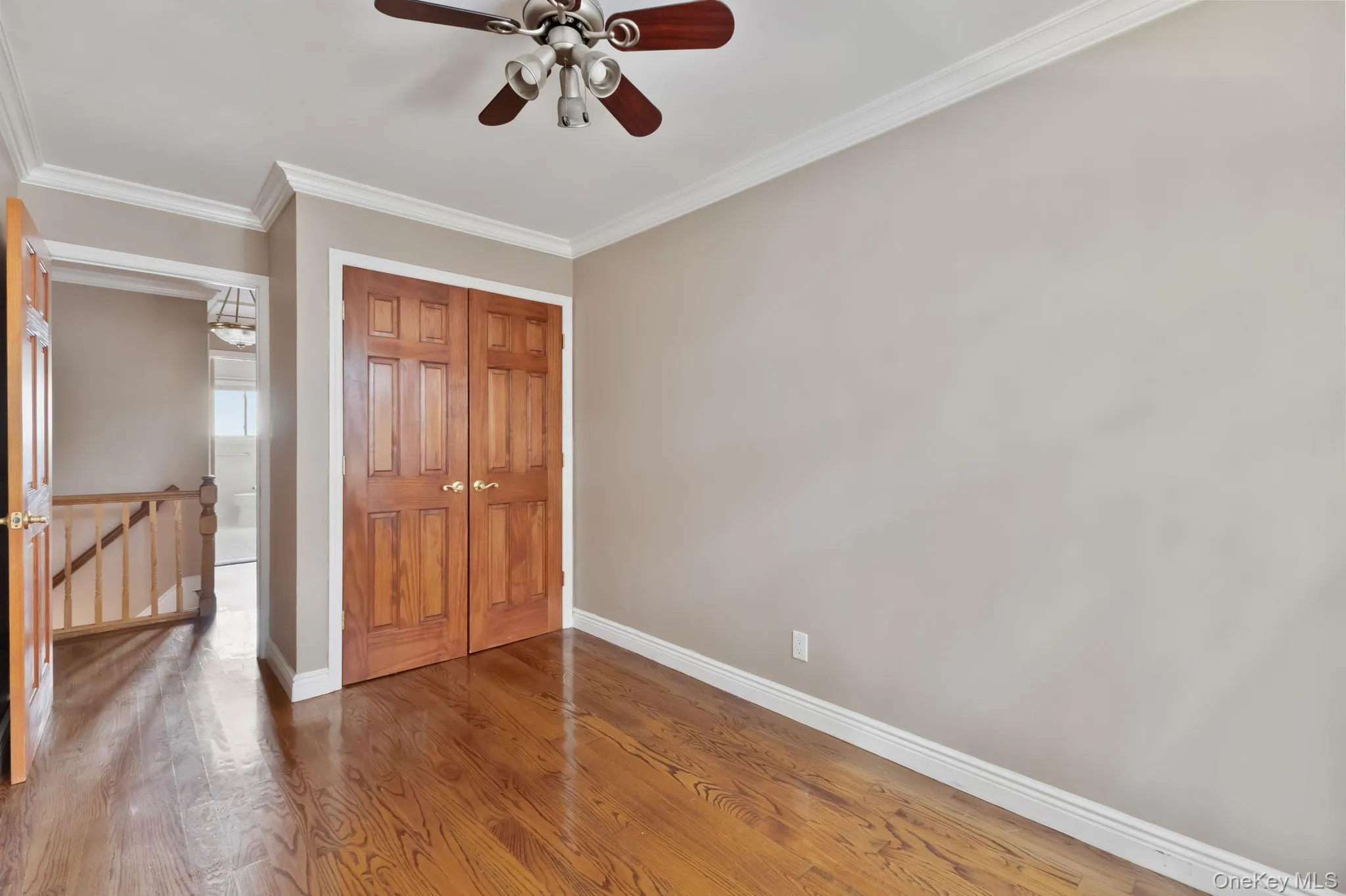 Unfurnished bedroom with crown molding, wood finished floors, a closet, and ceiling fan Unfurnished bedroom with crown molding, wood finished floors, a closet, and ceiling fan