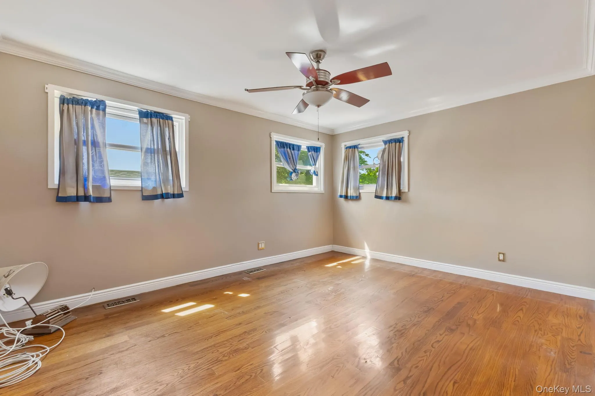 Spare room featuring ornamental molding, light wood-style floors, and a ceiling fan Spare room featuring ornamental molding, light wood-style floors, and a ceiling fan