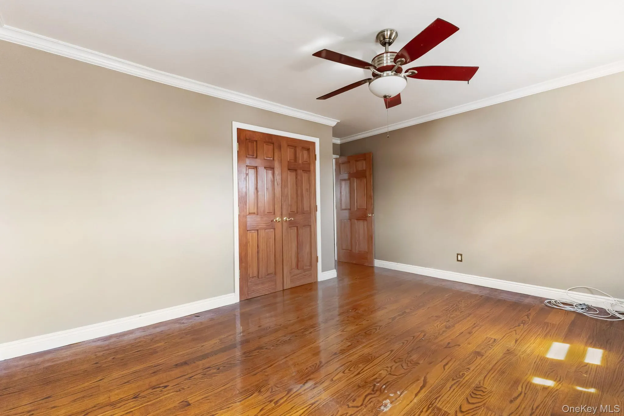 Unfurnished bedroom with crown molding, wood finished floors, a ceiling fan, and a closet Unfurnished bedroom with crown molding, wood finished floors, a ceiling fan, and a closet