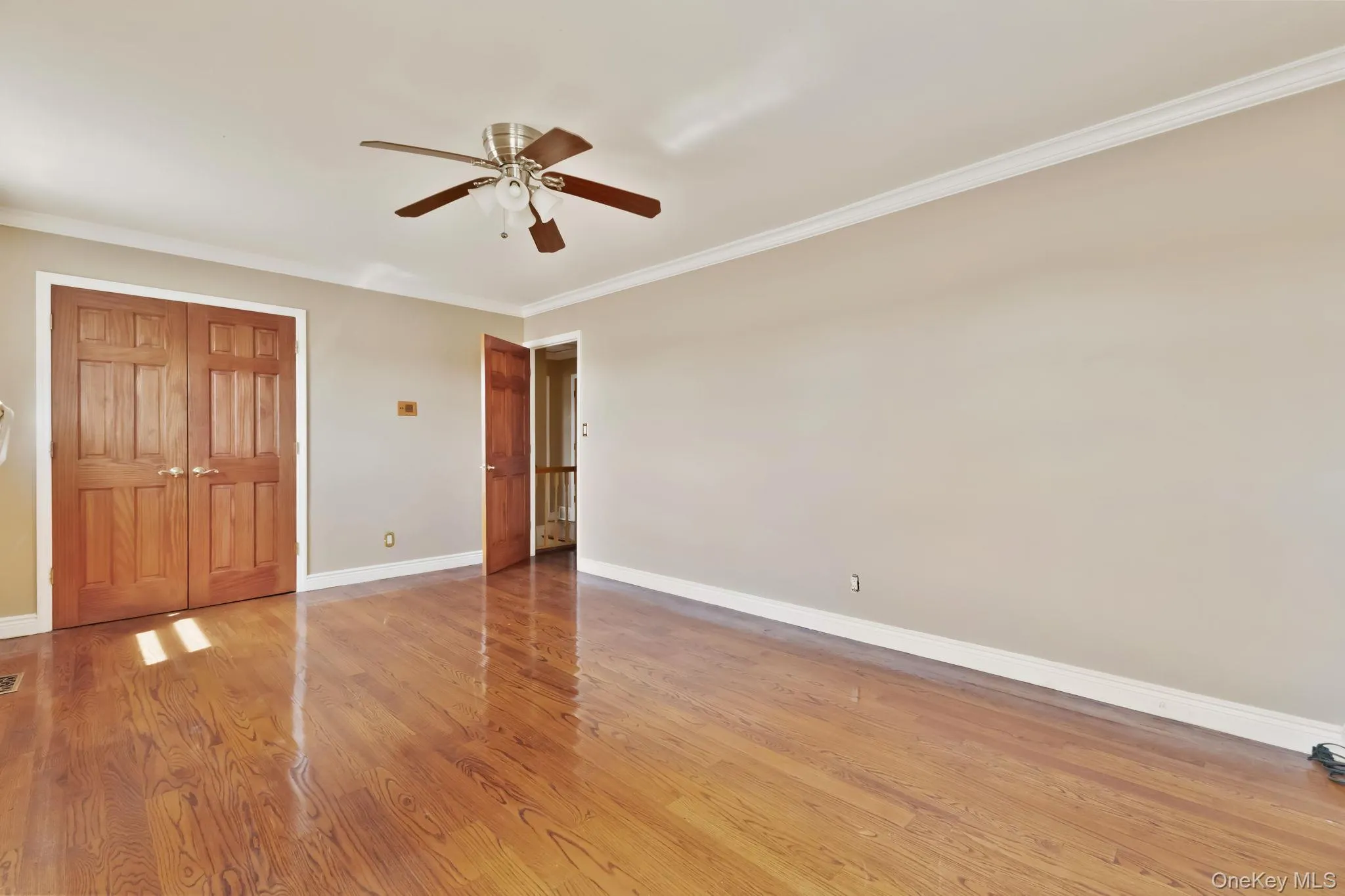 Unfurnished bedroom featuring crown molding, light wood finished floors, a ceiling fan, and a closet Unfurnished bedroom featuring crown molding, light wood finished floors, a ceiling fan, and a closet
