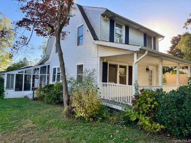 View of property exterior featuring a yard, a sunroom, and covered porch View of property exterior featuring a yard, a sunroom, and covered porch