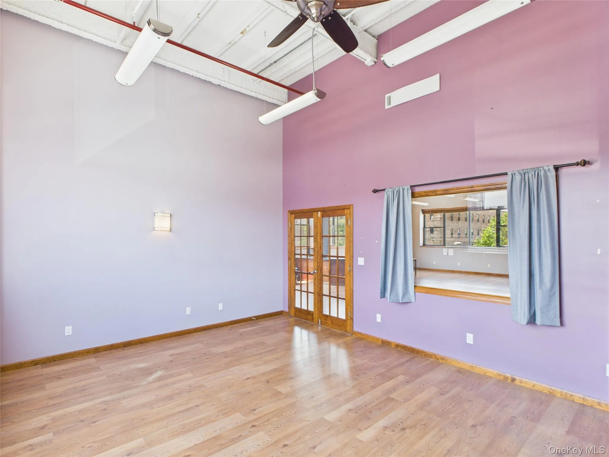 Spare room featuring light wood-style flooring, a ceiling fan, french doors, and a high ceiling Spare room featuring light wood-style flooring, a ceiling fan, french doors, and a high ceiling