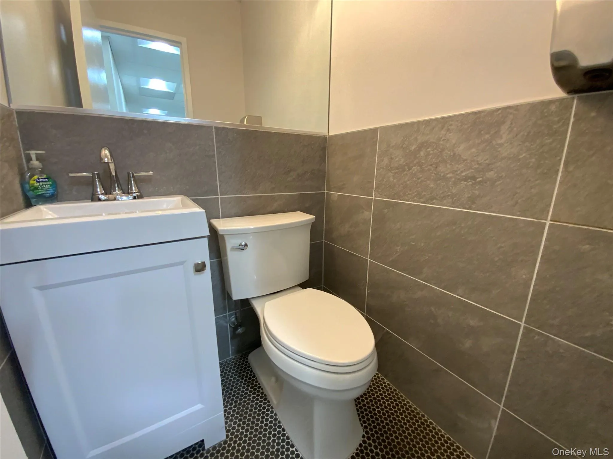 Bathroom with tile walls, vanity, tile patterned floors, and a wainscoted wall Bathroom with tile walls, vanity, tile patterned floors, and a wainscoted wall