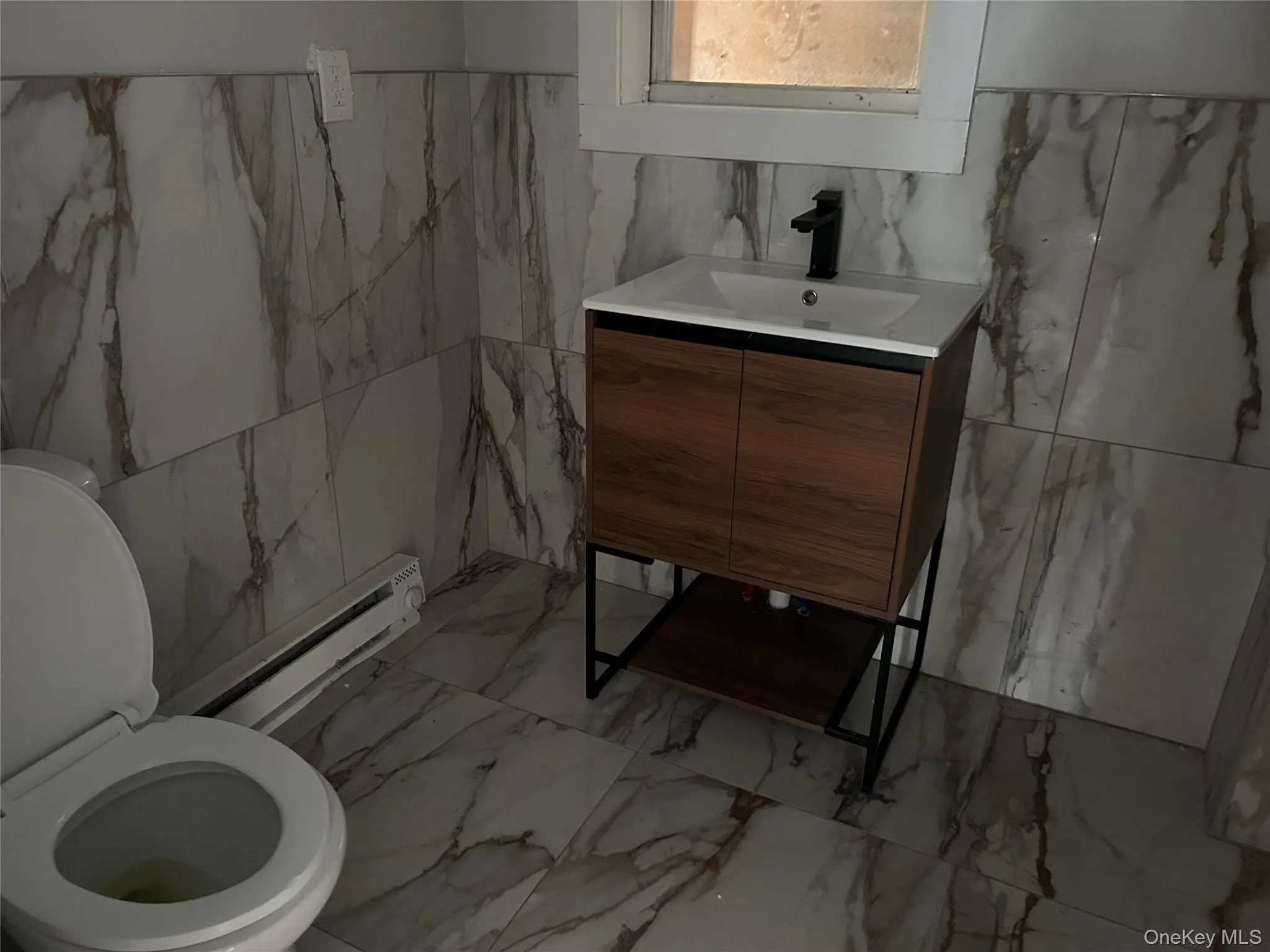 Bathroom featuring tile walls, vanity, marble finish floors, and baseboard heating Bathroom featuring tile walls, vanity, marble finish floors, and baseboard heating