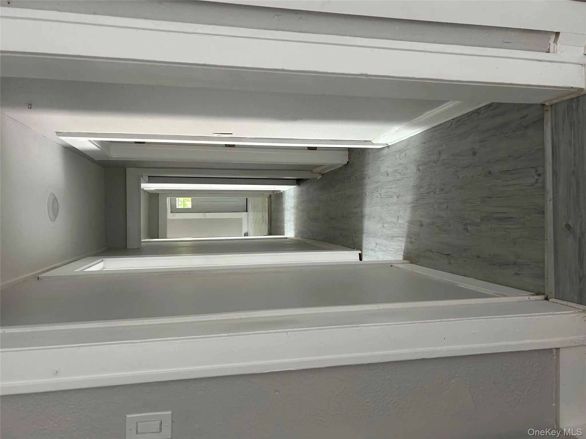 Hallway with light wood-style flooring and a textured wall Hallway with light wood-style flooring and a textured wall