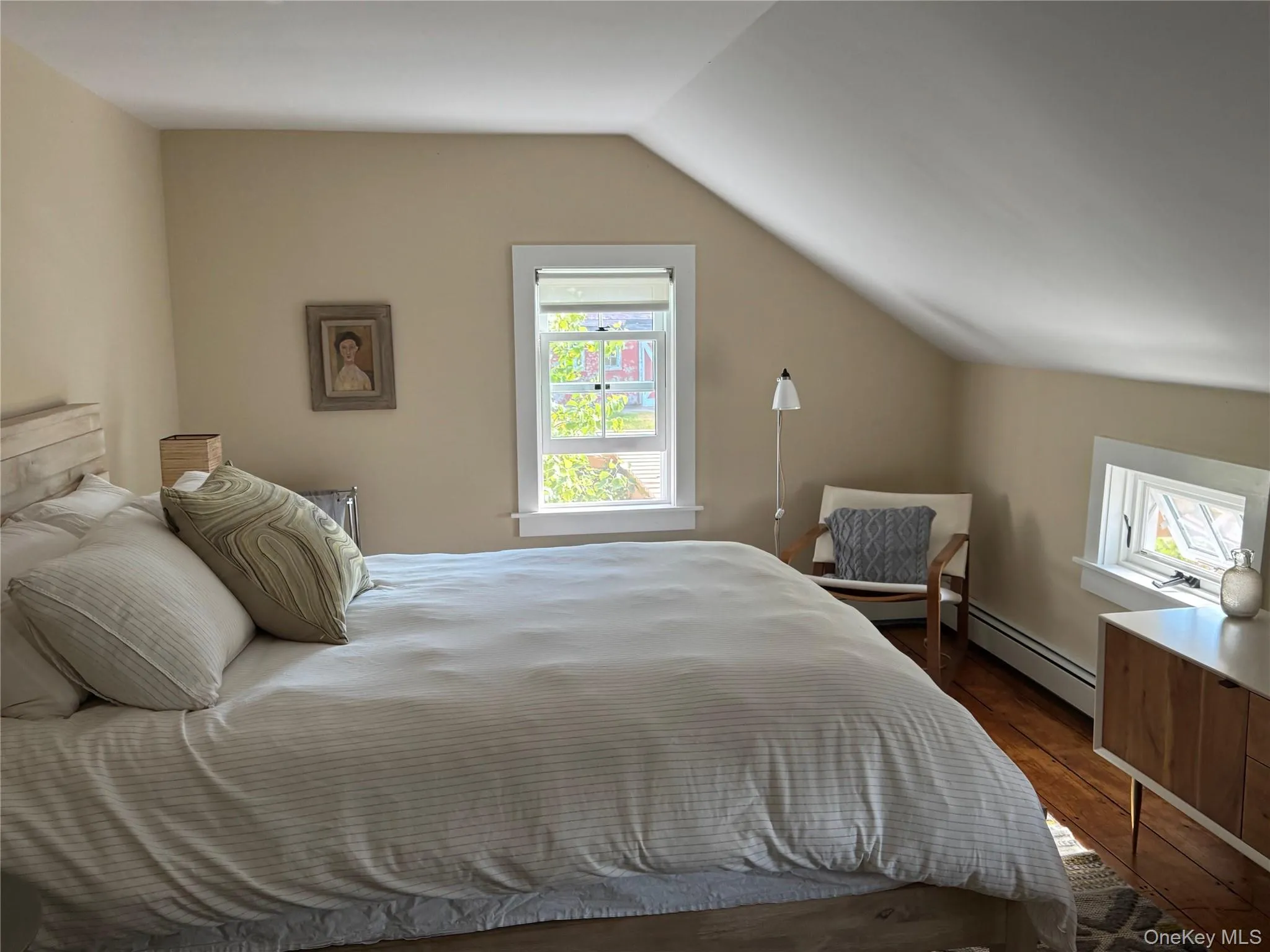 Bedroom featuring vaulted ceiling, dark wood-style floors, and a baseboard radiator Bedroom featuring vaulted ceiling, dark wood-style floors, and a baseboard radiator