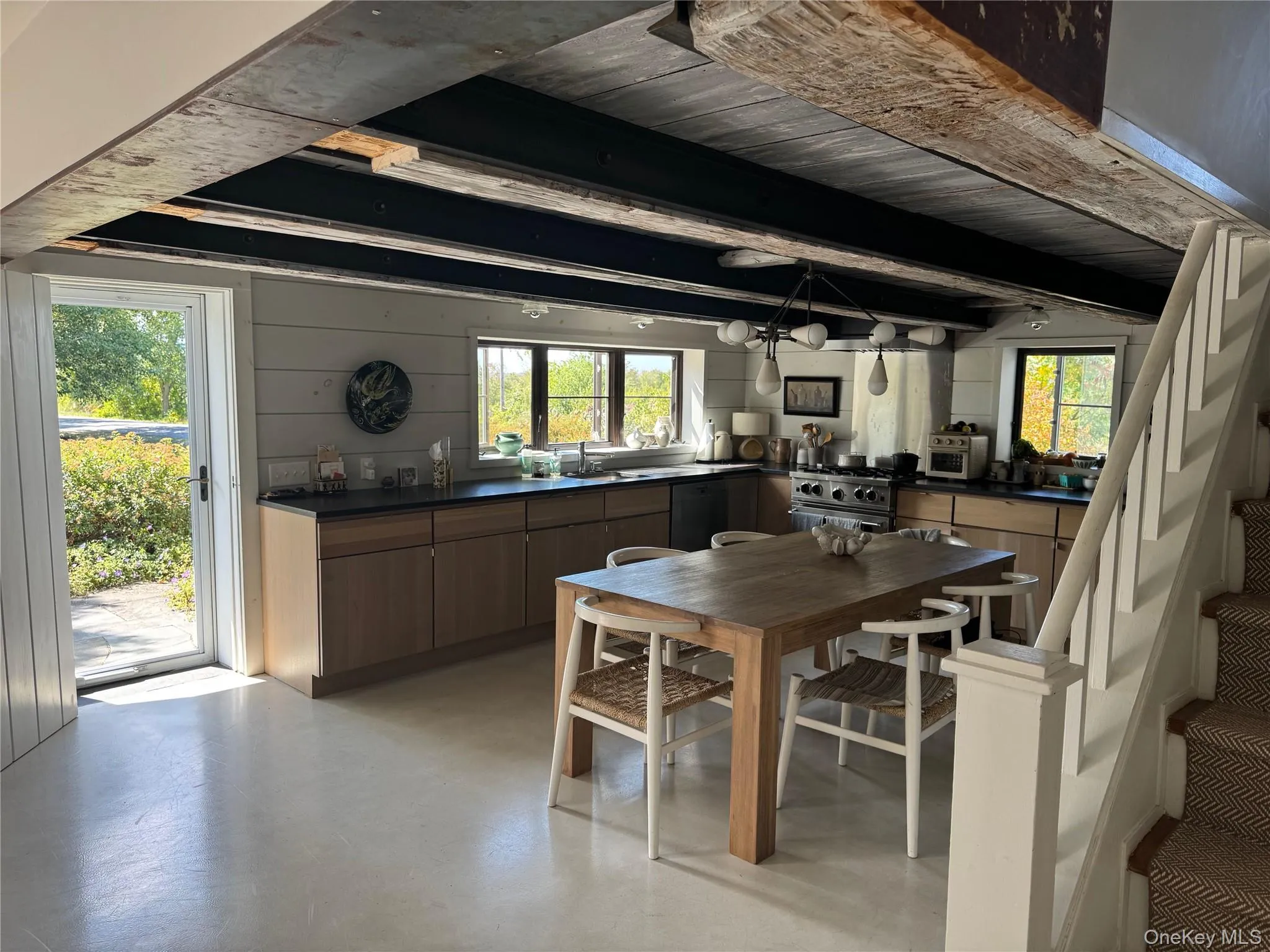 Dining room featuring stairway, beam ceiling, finished concrete flooring, and wooden walls Dining room featuring stairway, beam ceiling, finished concrete flooring, and wooden walls