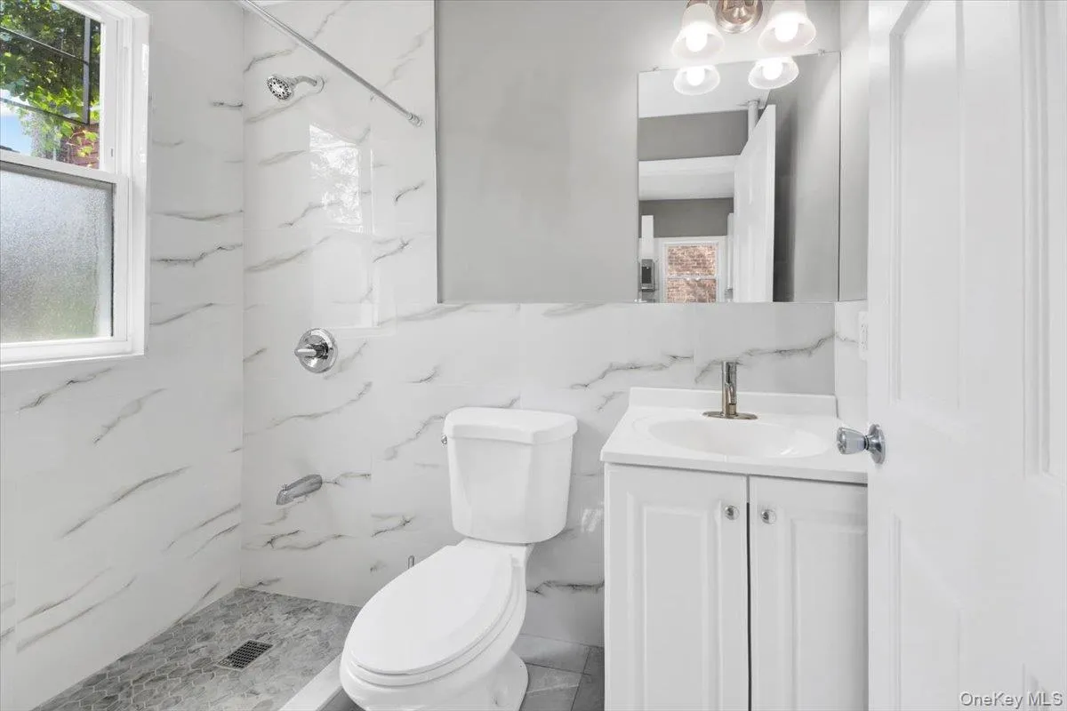 Bathroom with vanity, a marble finish shower, and tile walls Bathroom with vanity, a marble finish shower, and tile walls