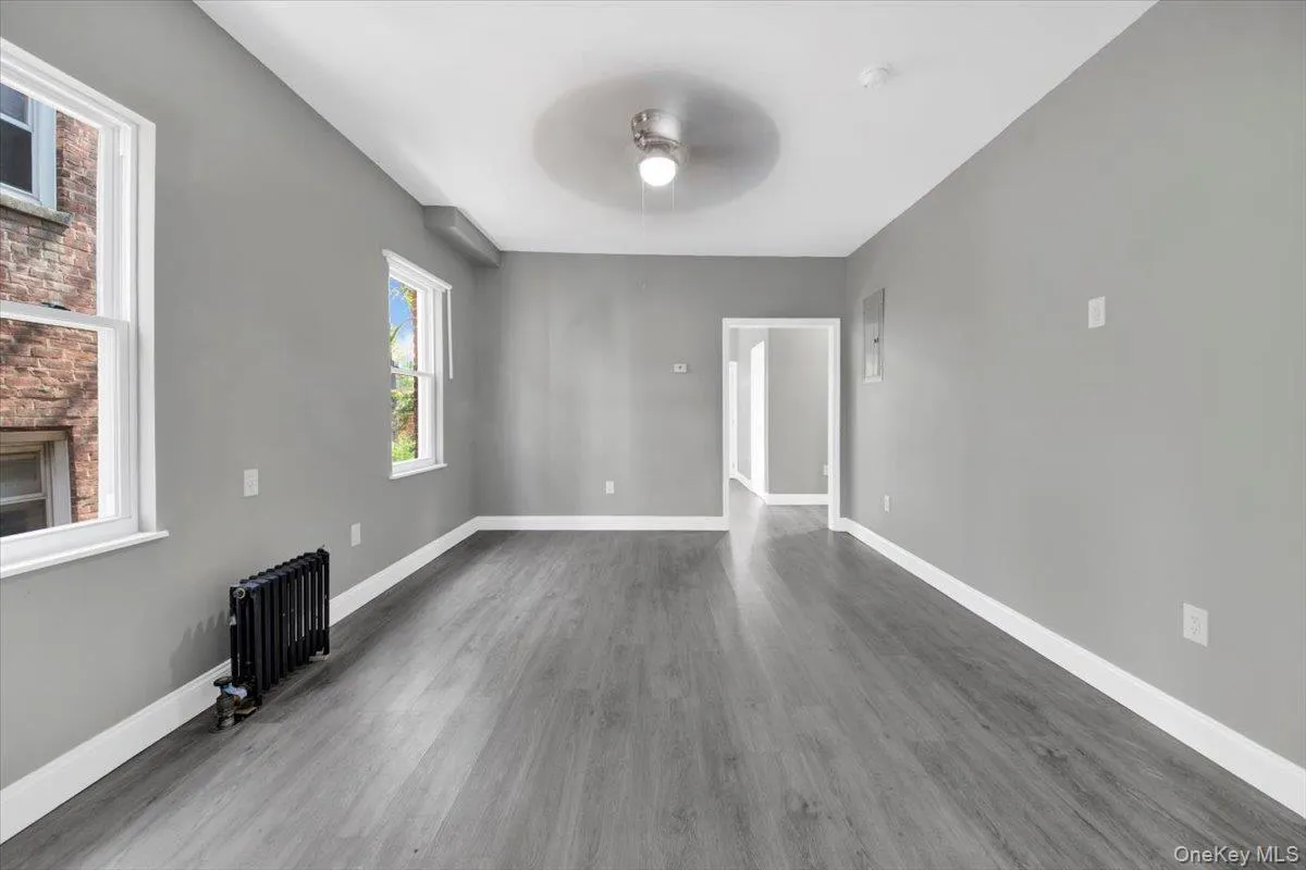 Unfurnished living room with radiator, wood finished floors, and ceiling fan Unfurnished living room with radiator, wood finished floors, and ceiling fan