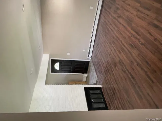 Unfurnished living room with dark wood-style floors, a baseboard radiator, a fireplace, and recessed lighting Unfurnished living room with dark wood-style floors, a baseboard radiator, a fireplace, and recessed lighting