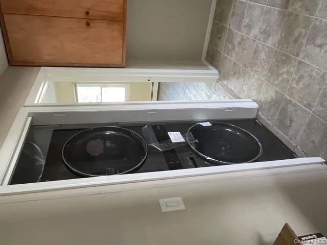 Laundry area featuring stacked washer and clothes dryer and baseboards Laundry area featuring stacked washer and clothes dryer and baseboards