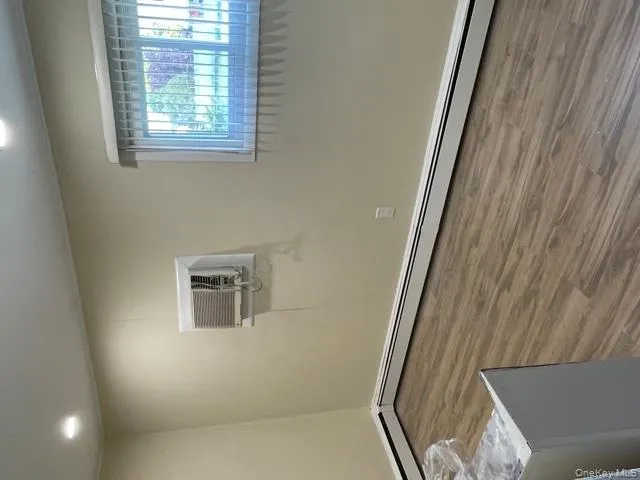 Unfurnished room featuring a baseboard radiator, dark wood-style flooring, recessed lighting, and an AC wall unit Unfurnished room featuring a baseboard radiator, dark wood-style flooring, recessed lighting, and an AC wall unit