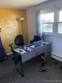 Office area with a baseboard radiator and dark colored carpet Office area with a baseboard radiator and dark colored carpet