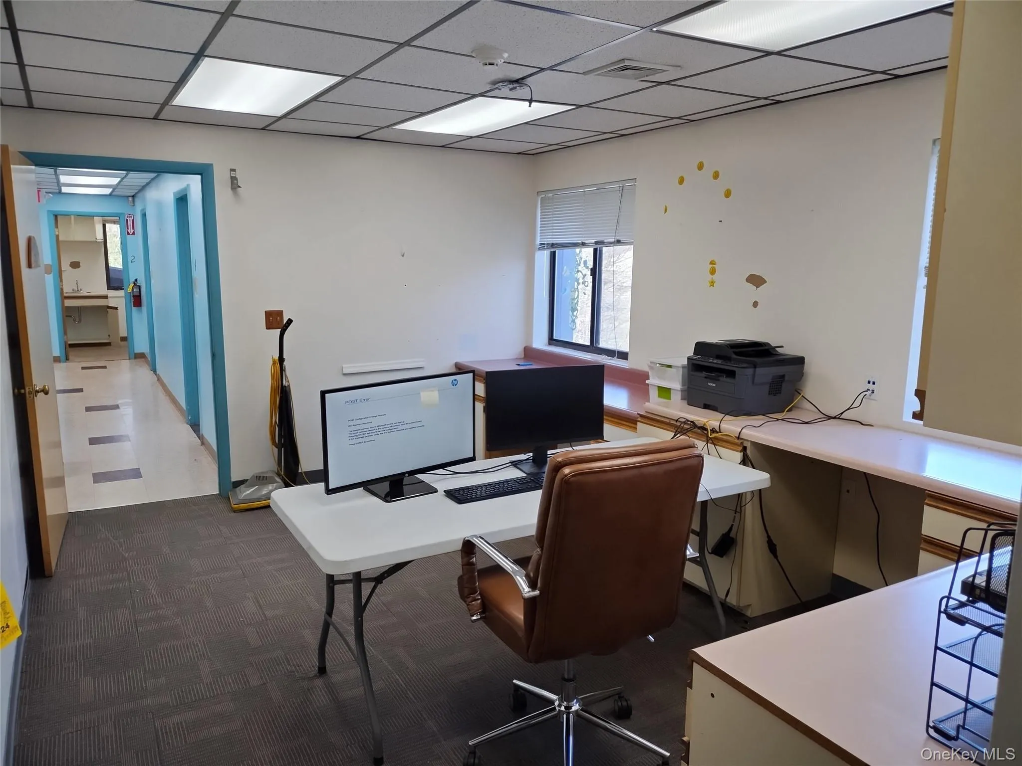 Office area featuring a paneled ceiling and dark carpet Office area featuring a paneled ceiling and dark carpet