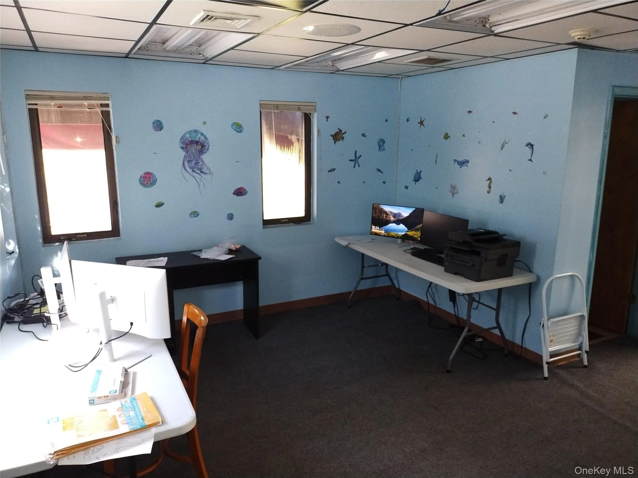 Office area featuring a paneled ceiling and dark colored carpet Office area featuring a paneled ceiling and dark colored carpet