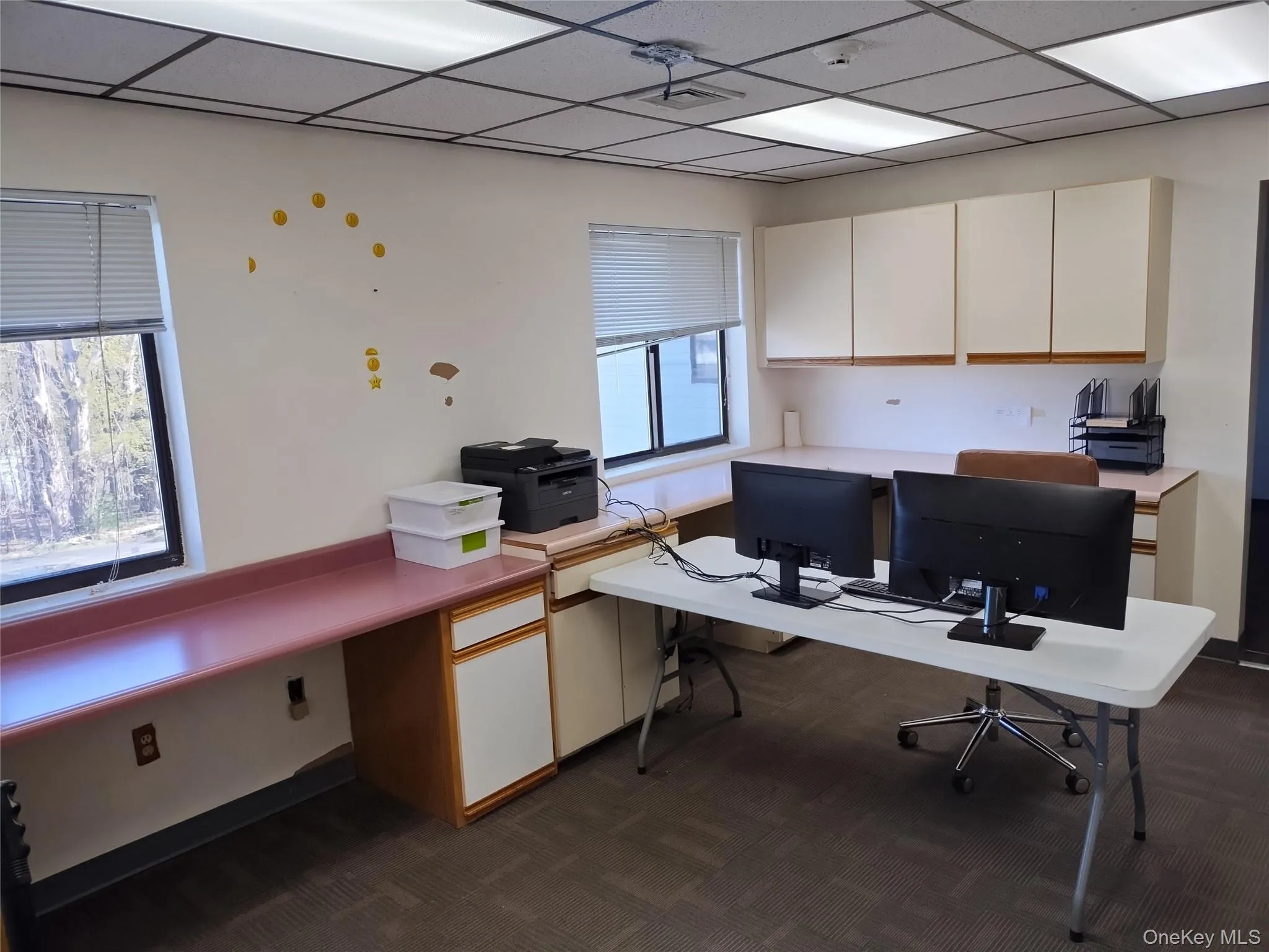 Office area with dark carpet, a drop ceiling, and built in study area Office area with dark carpet, a drop ceiling, and built in study area