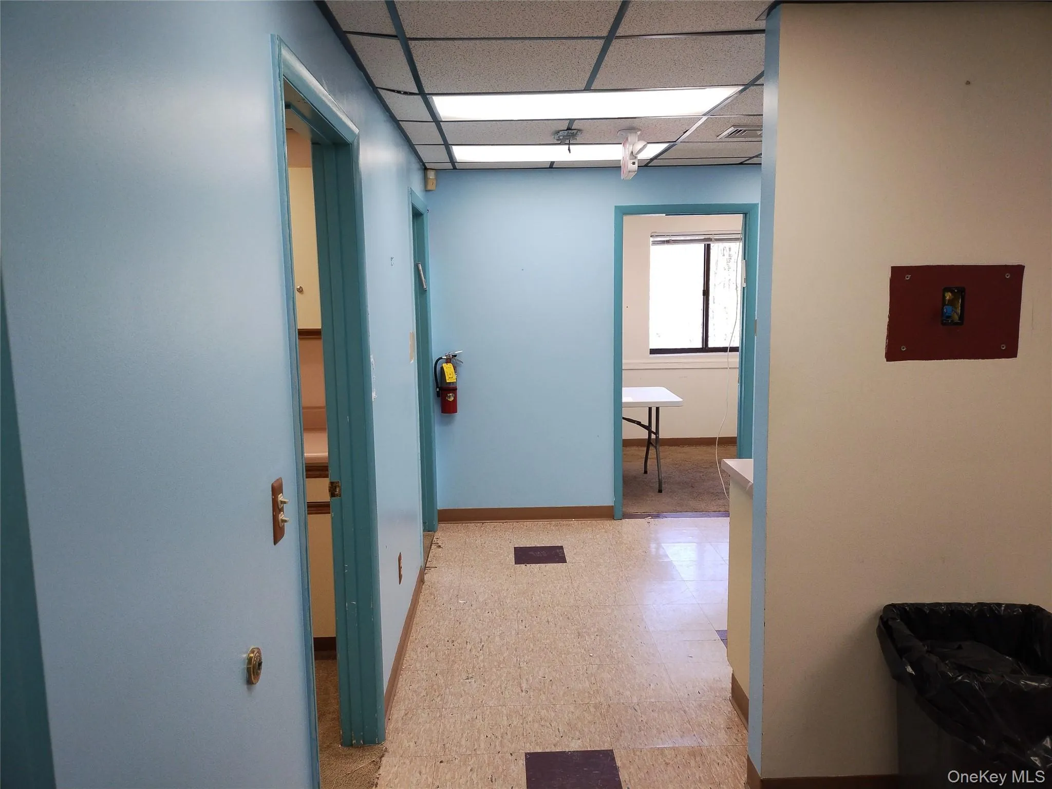 Hallway with light floors and a drop ceiling Hallway with light floors and a drop ceiling