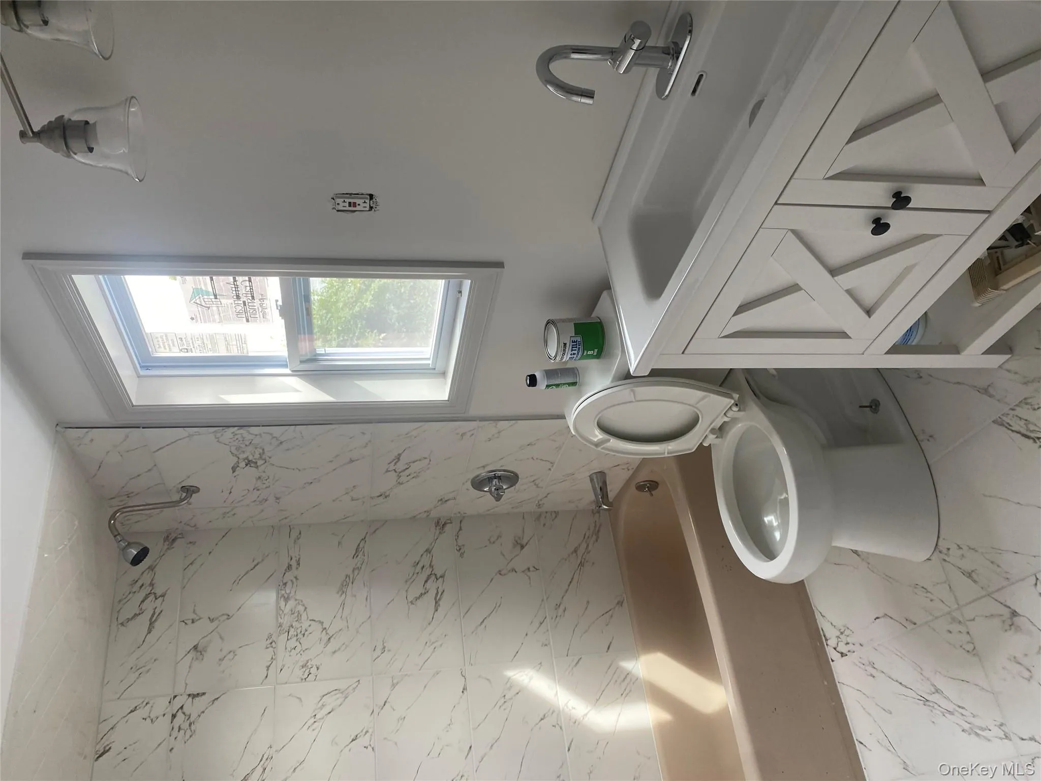 Bathroom with bathing tub / shower combination, vanity, and light marble finish floors Bathroom with bathing tub / shower combination, vanity, and light marble finish floors