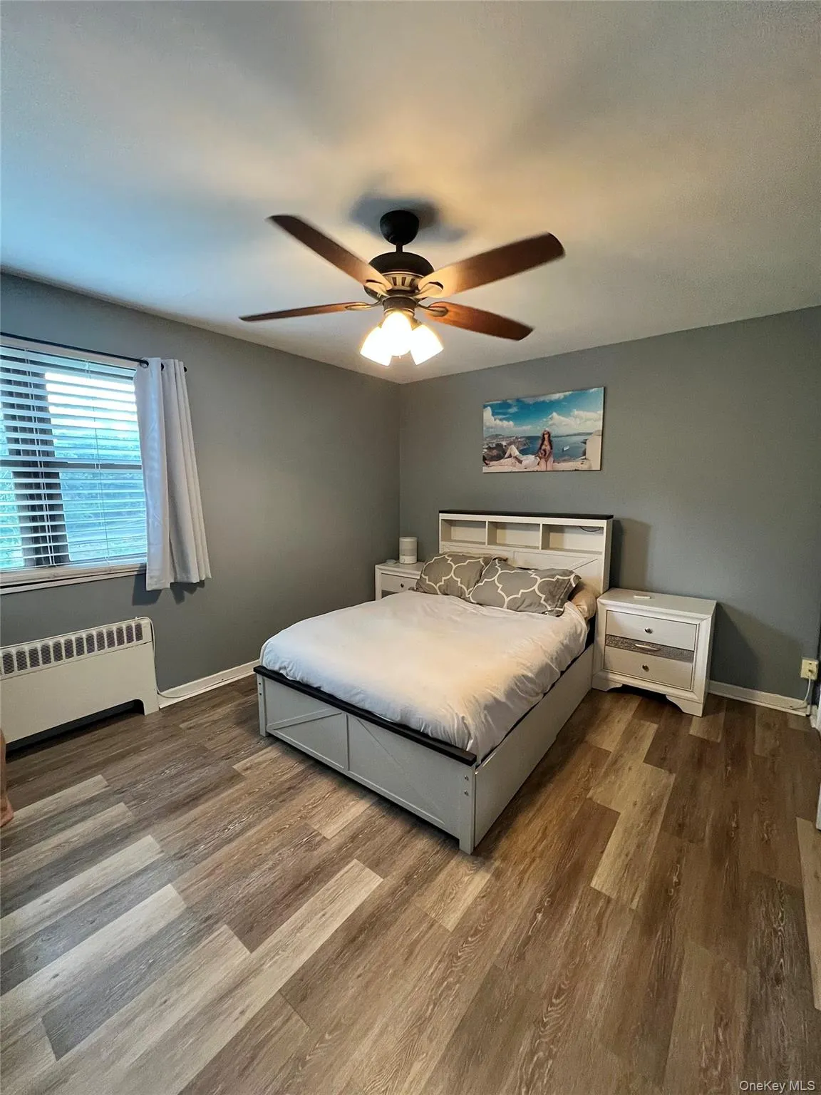 Bedroom with radiator, ceiling fan, and laminated finished floors Bedroom with radiator, ceiling fan, and laminated finished floors
