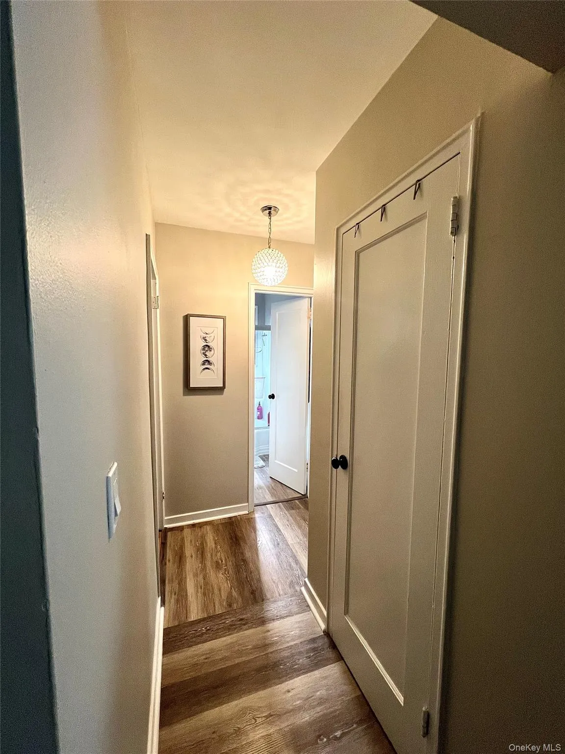 Hallway featuring dark wood laminated finished floors and baseboards Hallway featuring dark wood laminated finished floors and baseboards