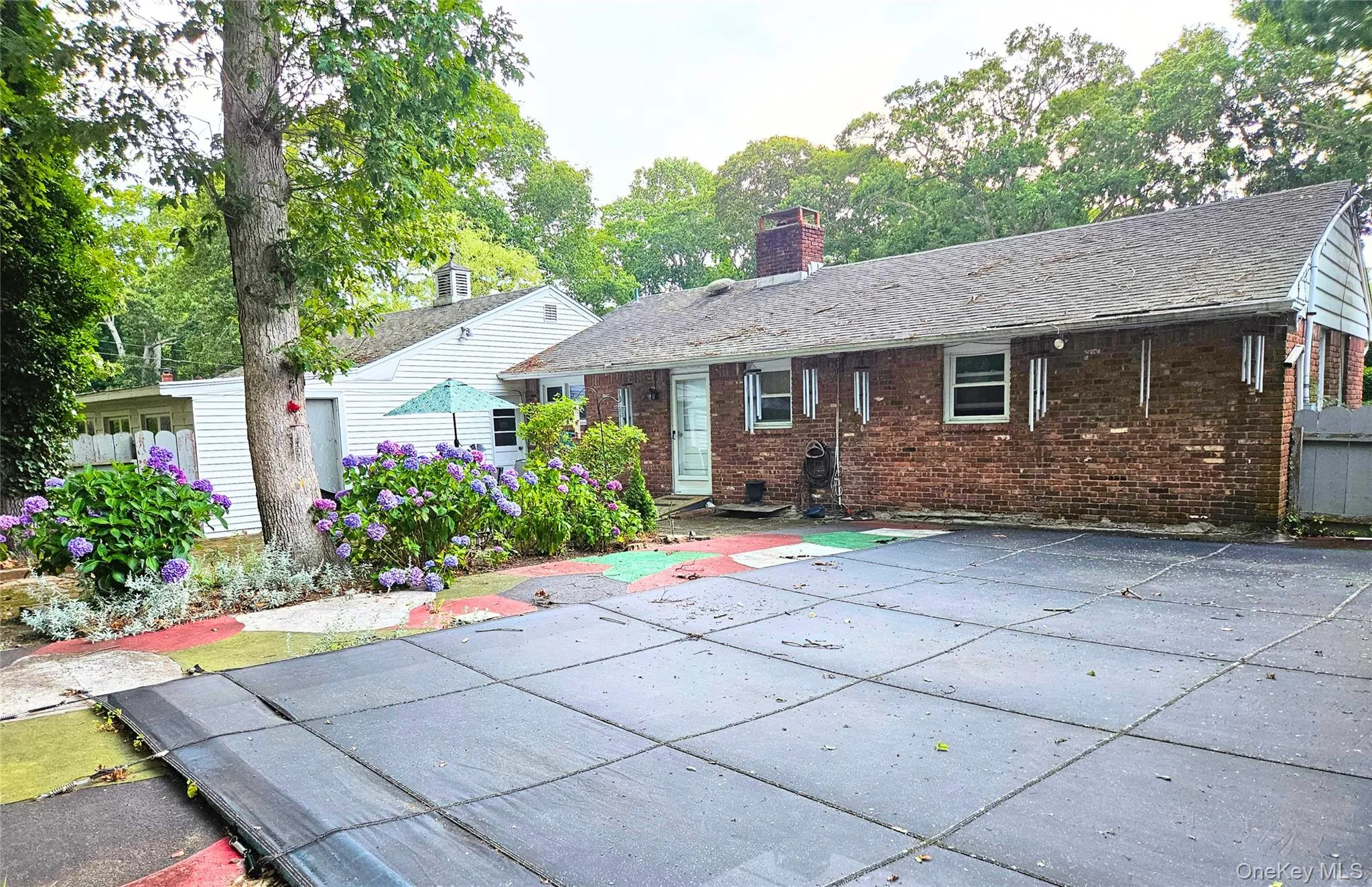 Back of property featuring  brick siding, a patio area, and a covered pool