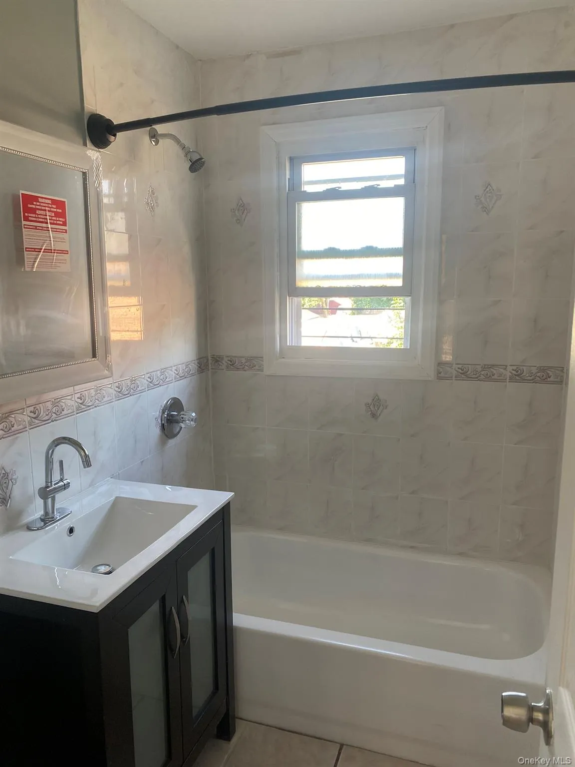 Full bath featuring vanity, shower / bath combination, tile walls, light tile patterned floors, and backsplash Full bath featuring vanity, shower / bath combination, tile walls, light tile patterned floors, and backsplash