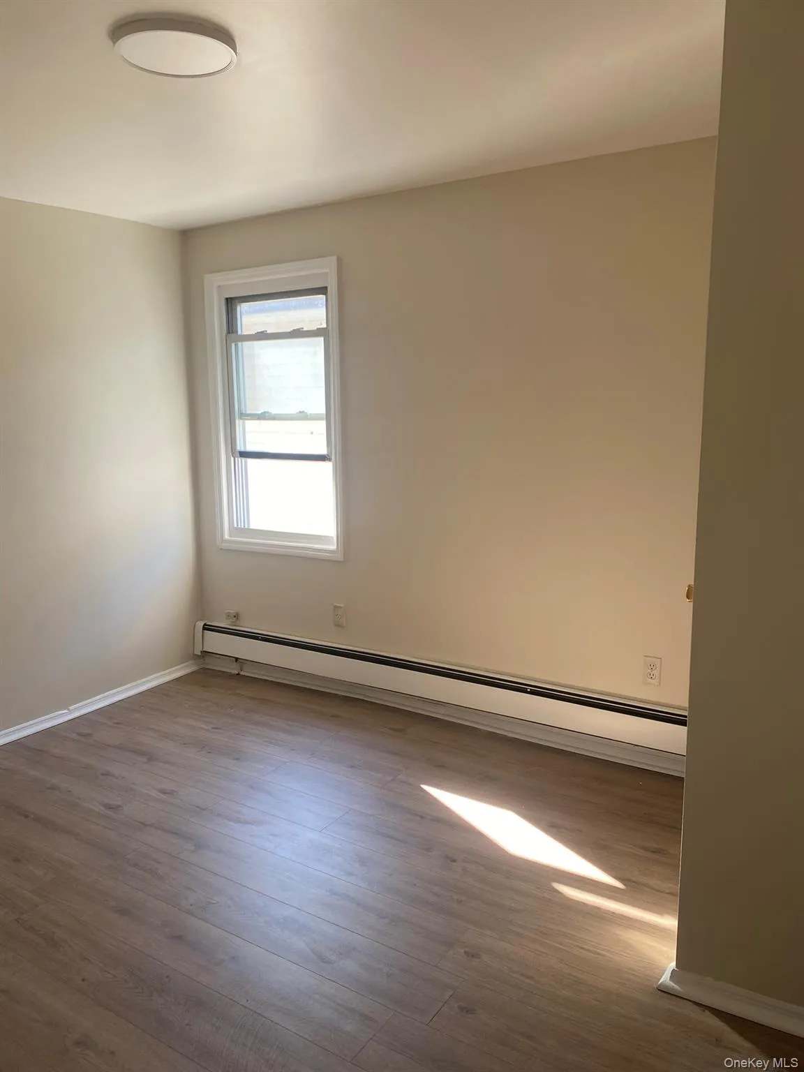Unfurnished room featuring a baseboard radiator and dark wood-type flooring Unfurnished room featuring a baseboard radiator and dark wood-type flooring