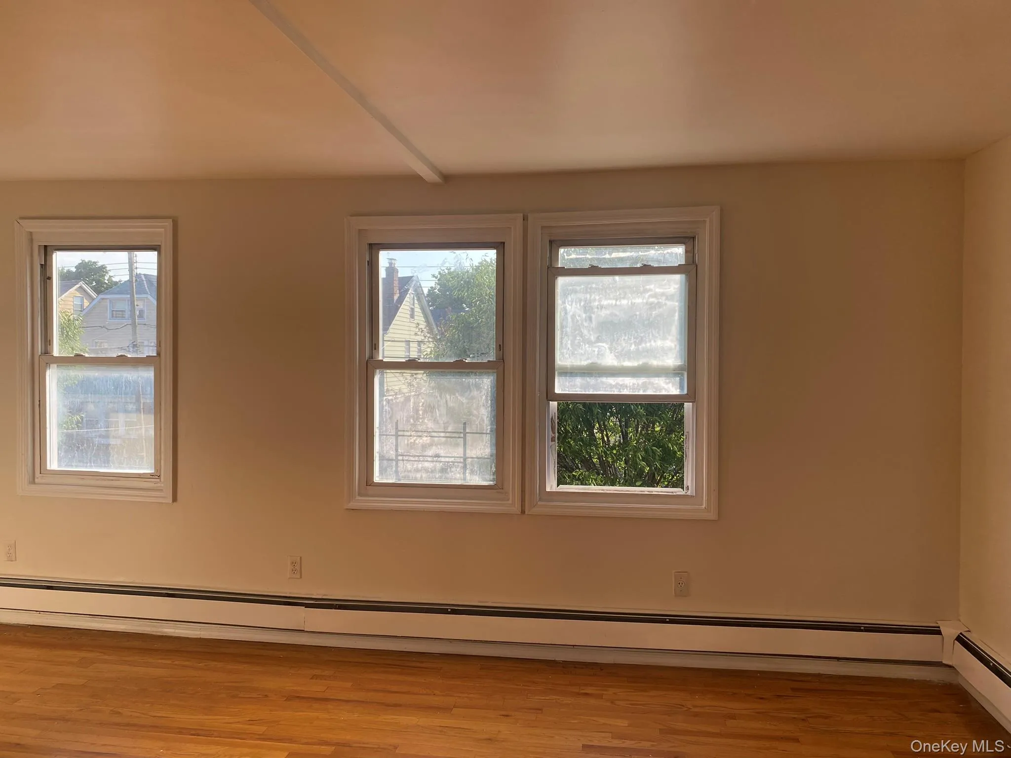 Unfurnished room with a baseboard radiator and light wood finished floors Unfurnished room with a baseboard radiator and light wood finished floors