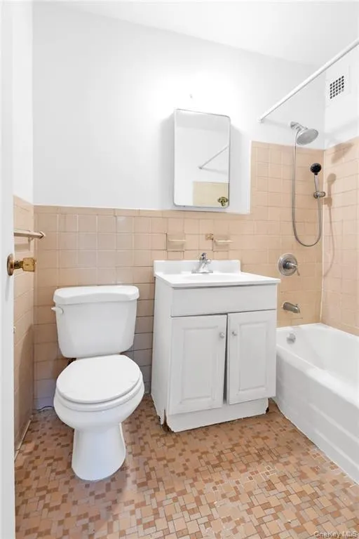 Bathroom with tile walls, bathing tub / shower combination, vanity, and wainscoting Bathroom with tile walls, bathing tub / shower combination, vanity, and wainscoting