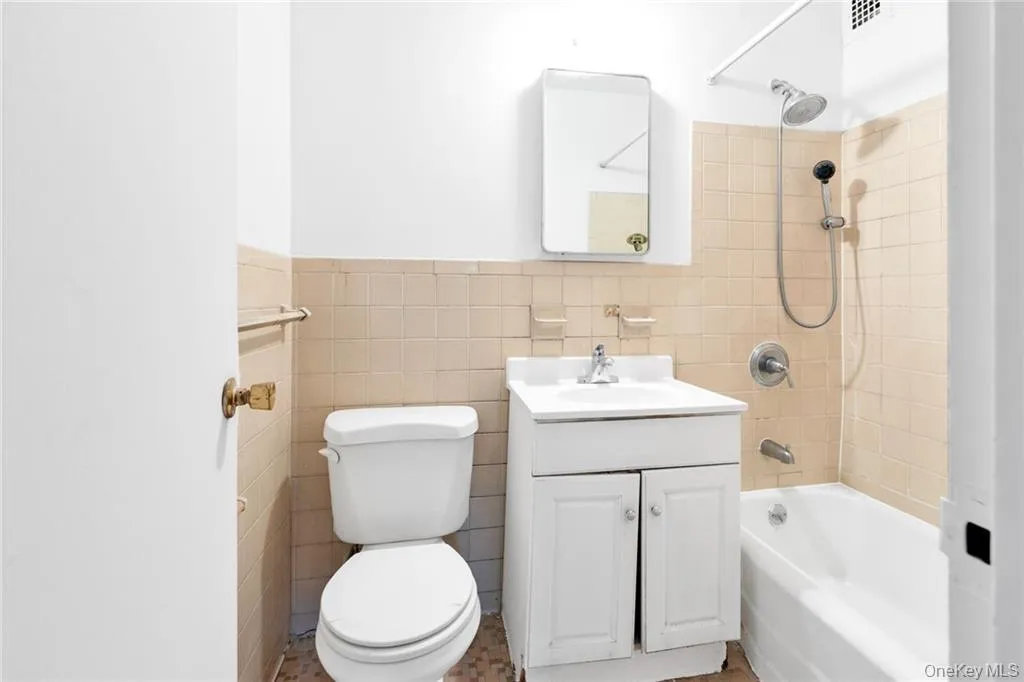 Bathroom with shower / tub combination, tile walls, vanity, and a wainscoted wall Bathroom with shower / tub combination, tile walls, vanity, and a wainscoted wall
