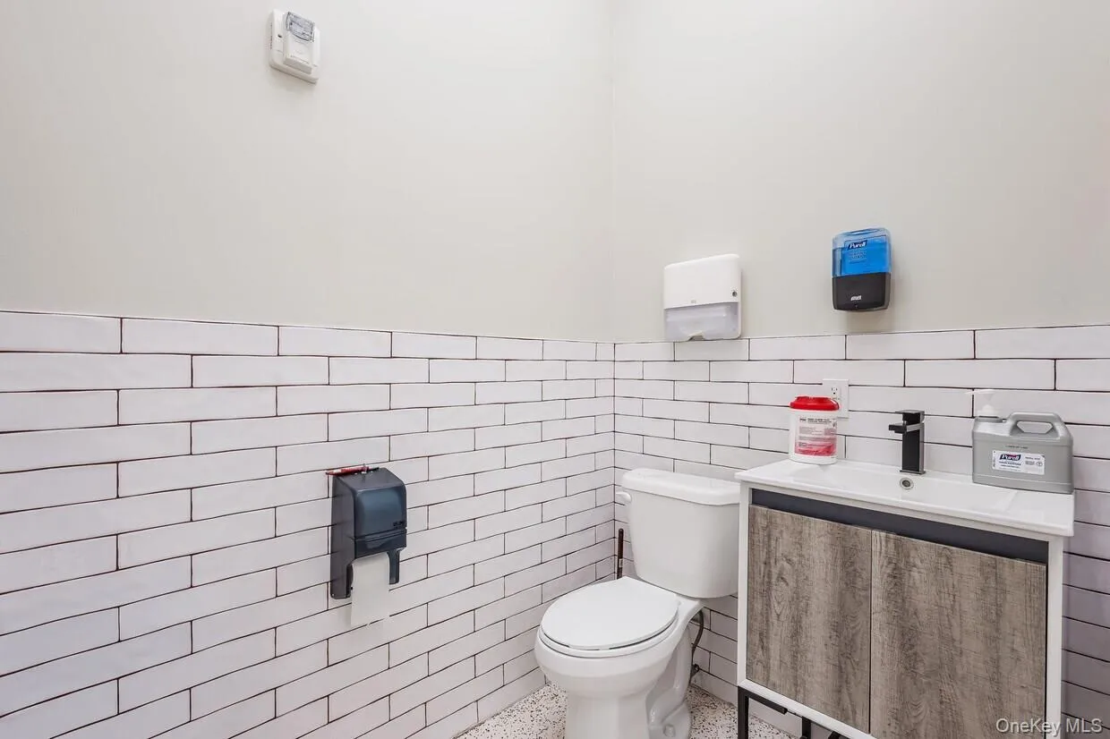 Half bath featuring vanity, tile walls, and wainscoting Half bath featuring vanity, tile walls, and wainscoting