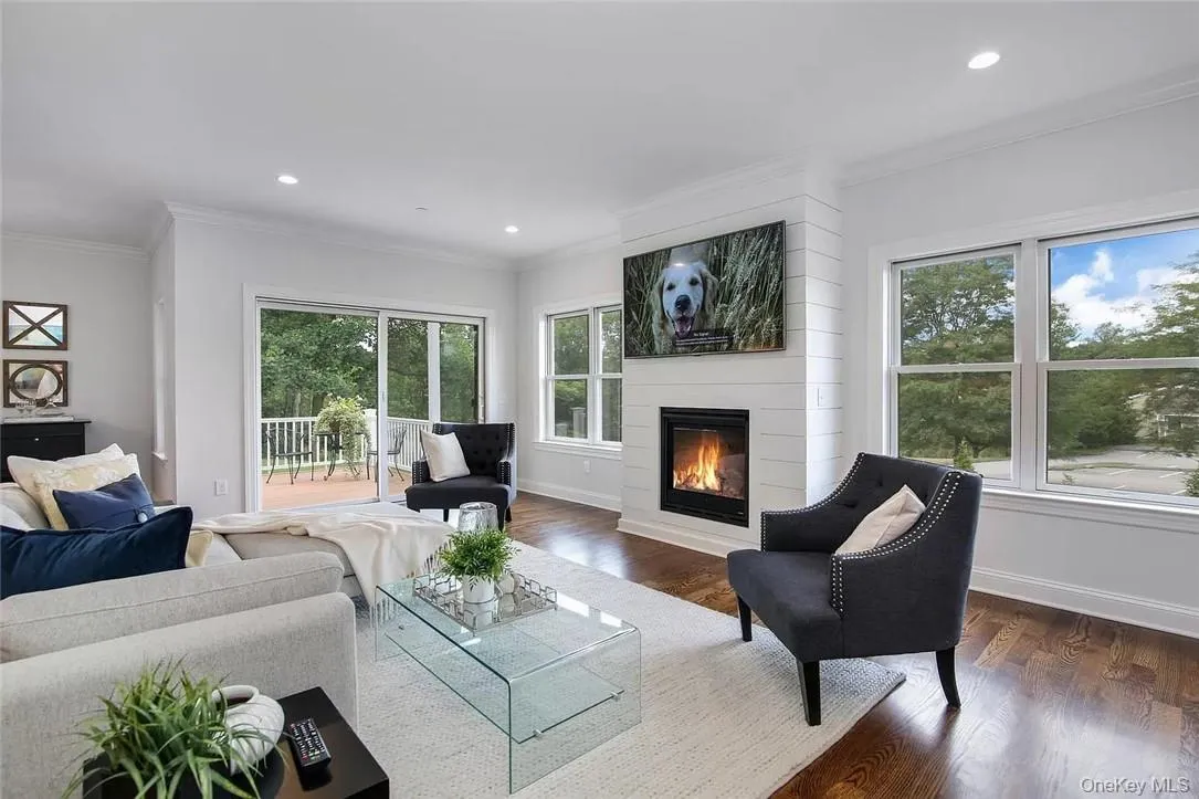 Living room featuring dark hardwood / wood-style floors, a large fireplace, and ornamental molding Living room featuring dark hardwood / wood-style floors, a large fireplace, and ornamental molding