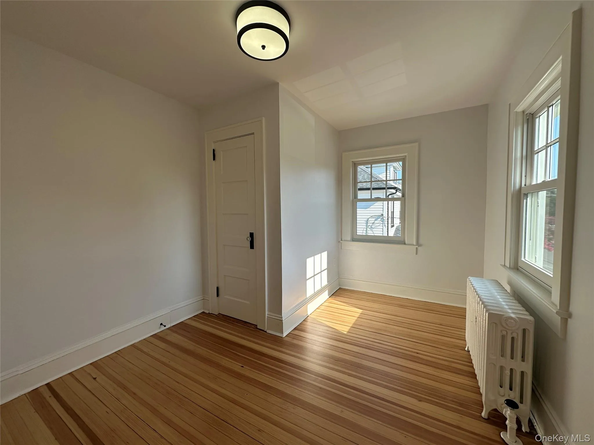 Additional living space with radiator heating unit and light wood finished floors Additional living space with radiator heating unit and light wood finished floors